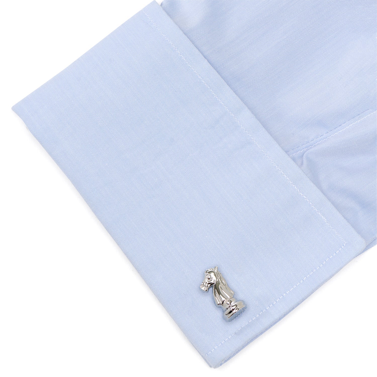 Silver horse-shaped cufflink on a light blue shirt cuff.