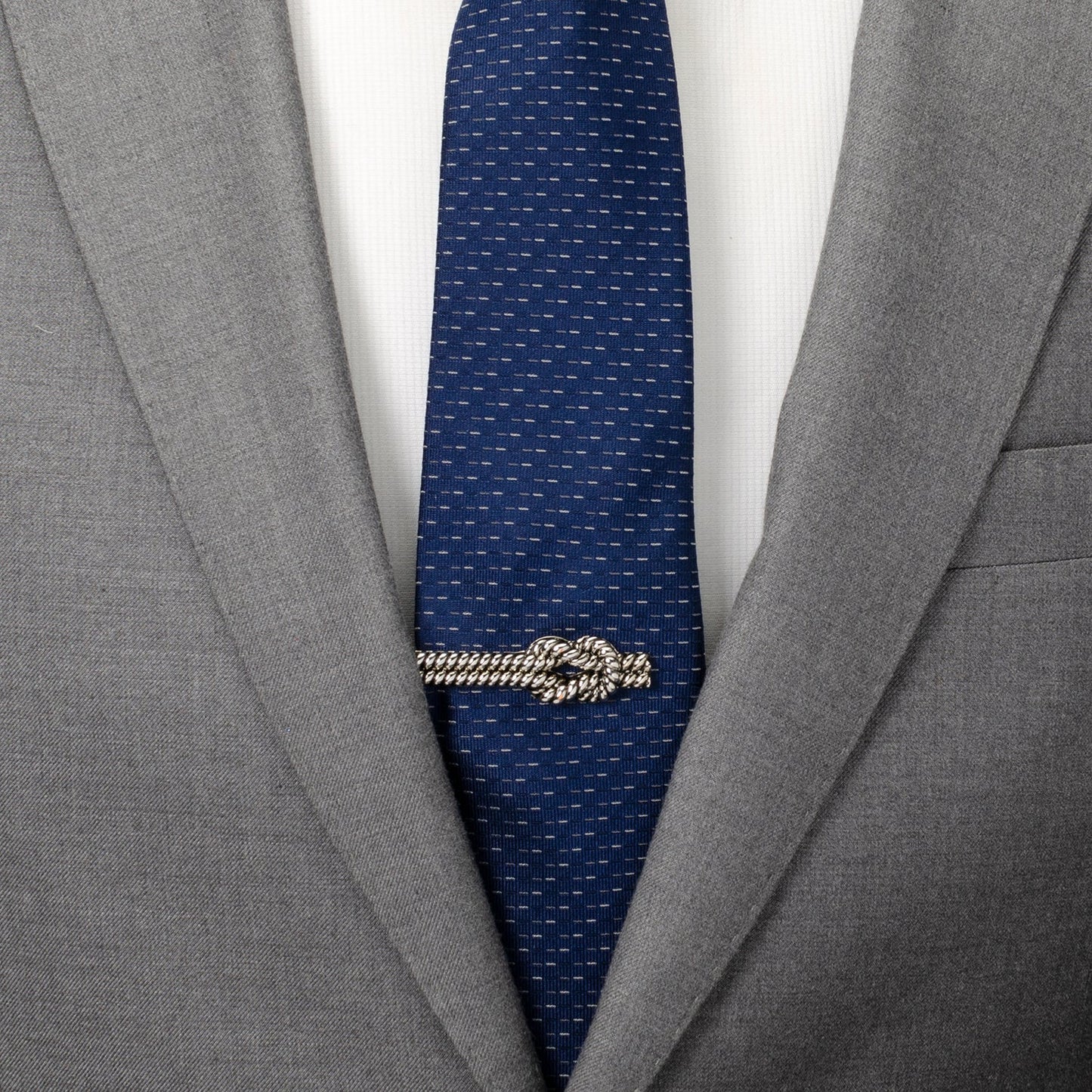 Gray suit jacket with a blue tie and gold tie clip on a white background