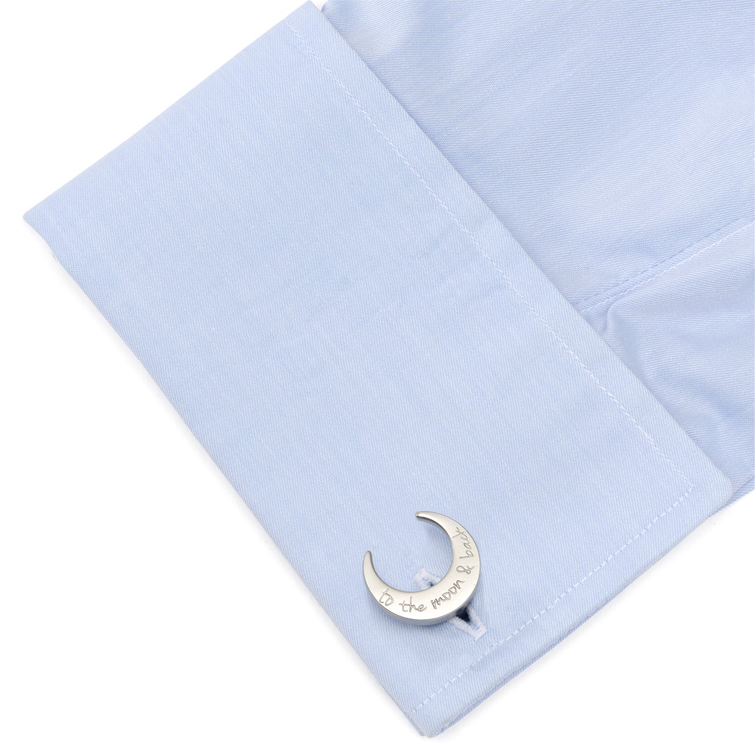 Cufflink shaped like a crescent moon on a light blue shirt cuff.