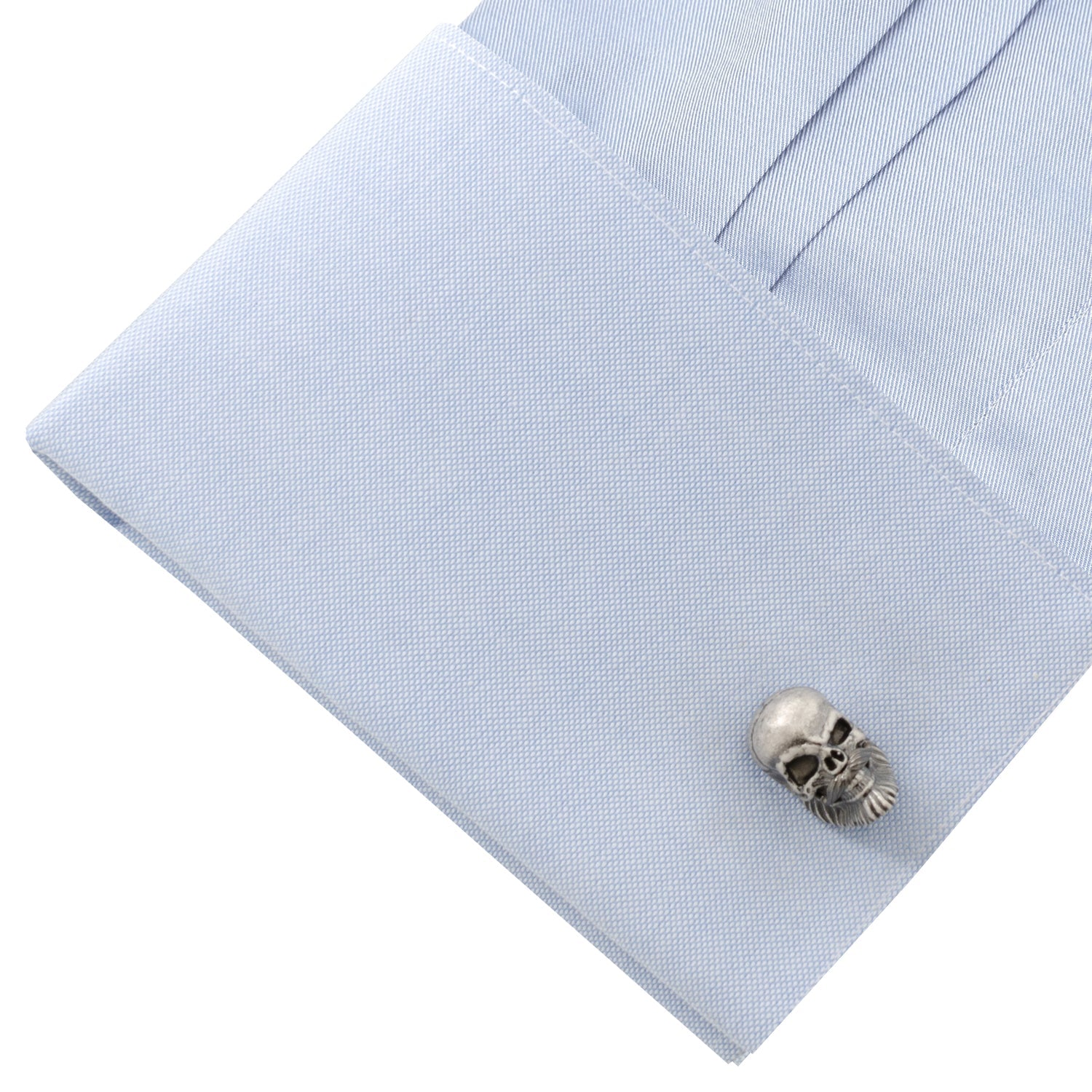 Skull-shaped cufflink on a light blue dress shirt