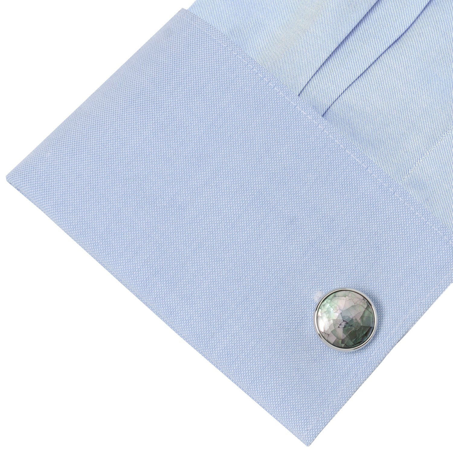 Close-up of a light blue pocket square with a round, textured cufflink on a white background