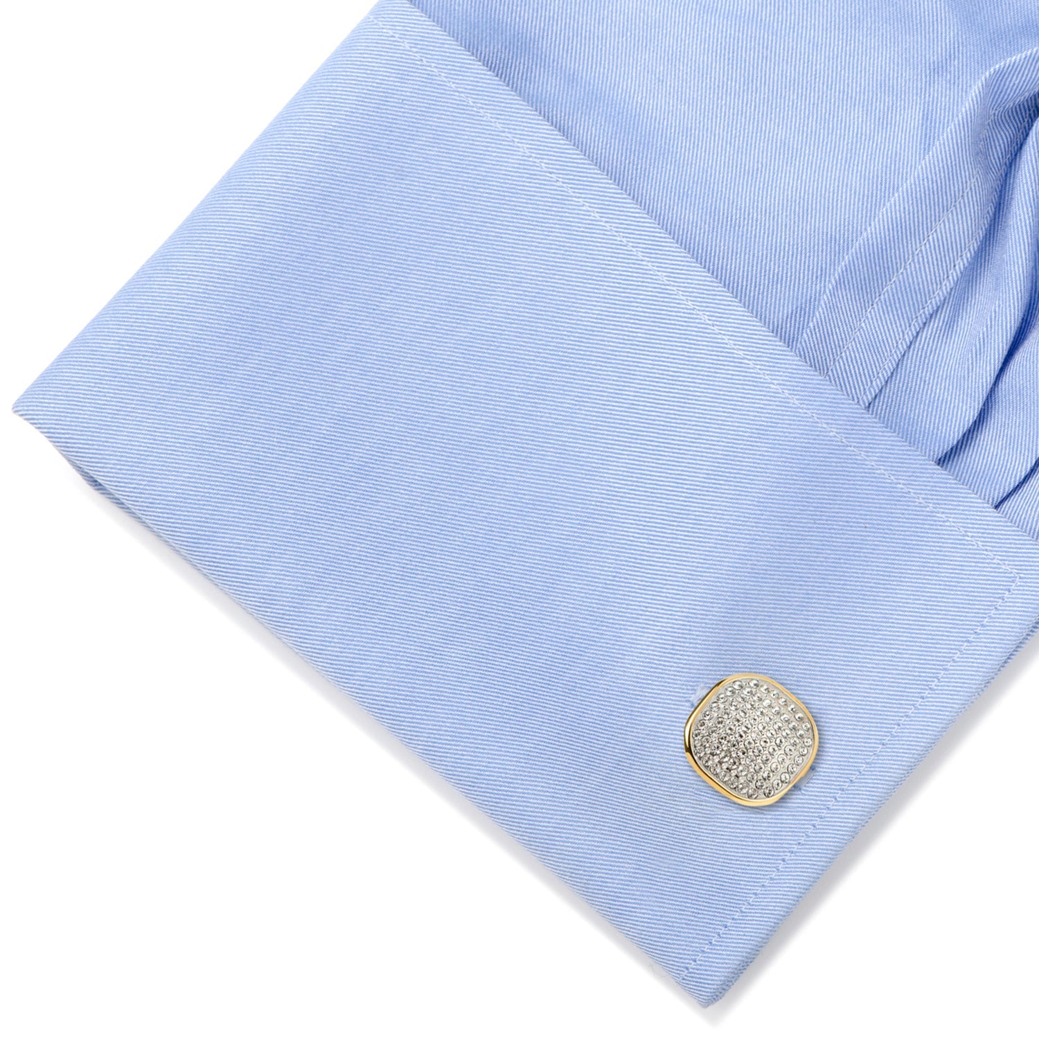Close-up of a light blue shirt with a decorative cufflink on a white background