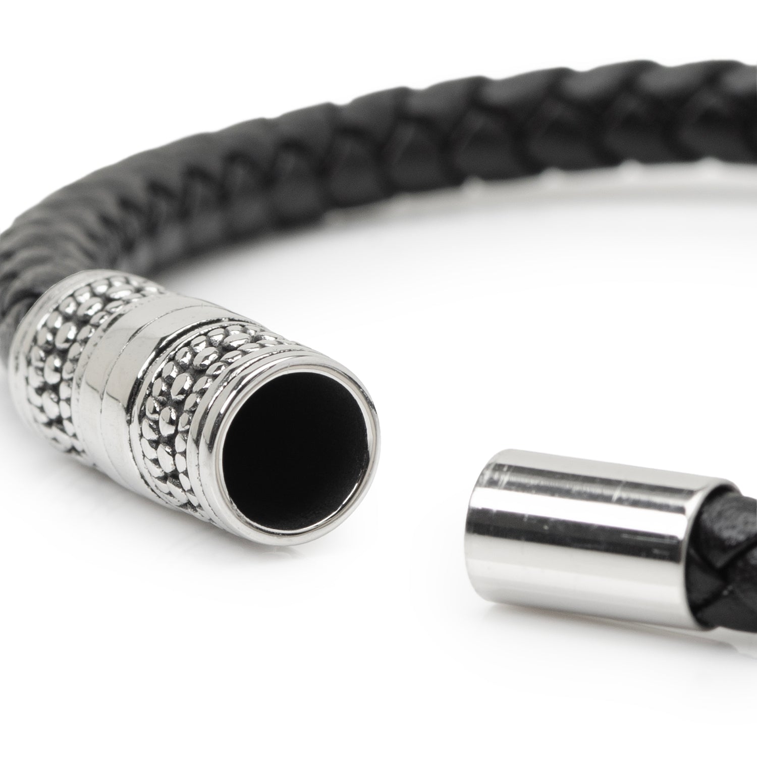 Close-up of a black braided leather bracelet with silver clasp on a white background