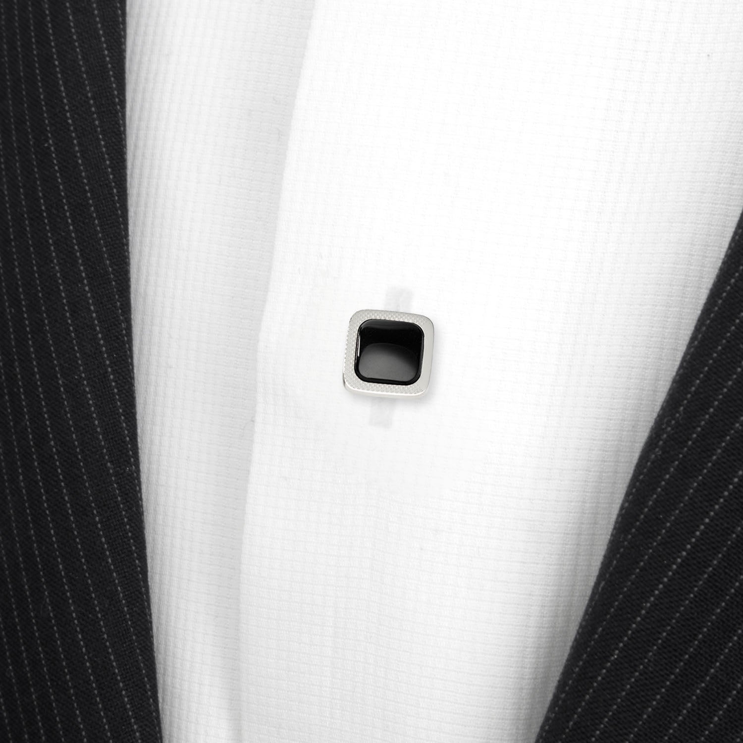 Close-up of a black square button on a white shirt with black pinstripes.