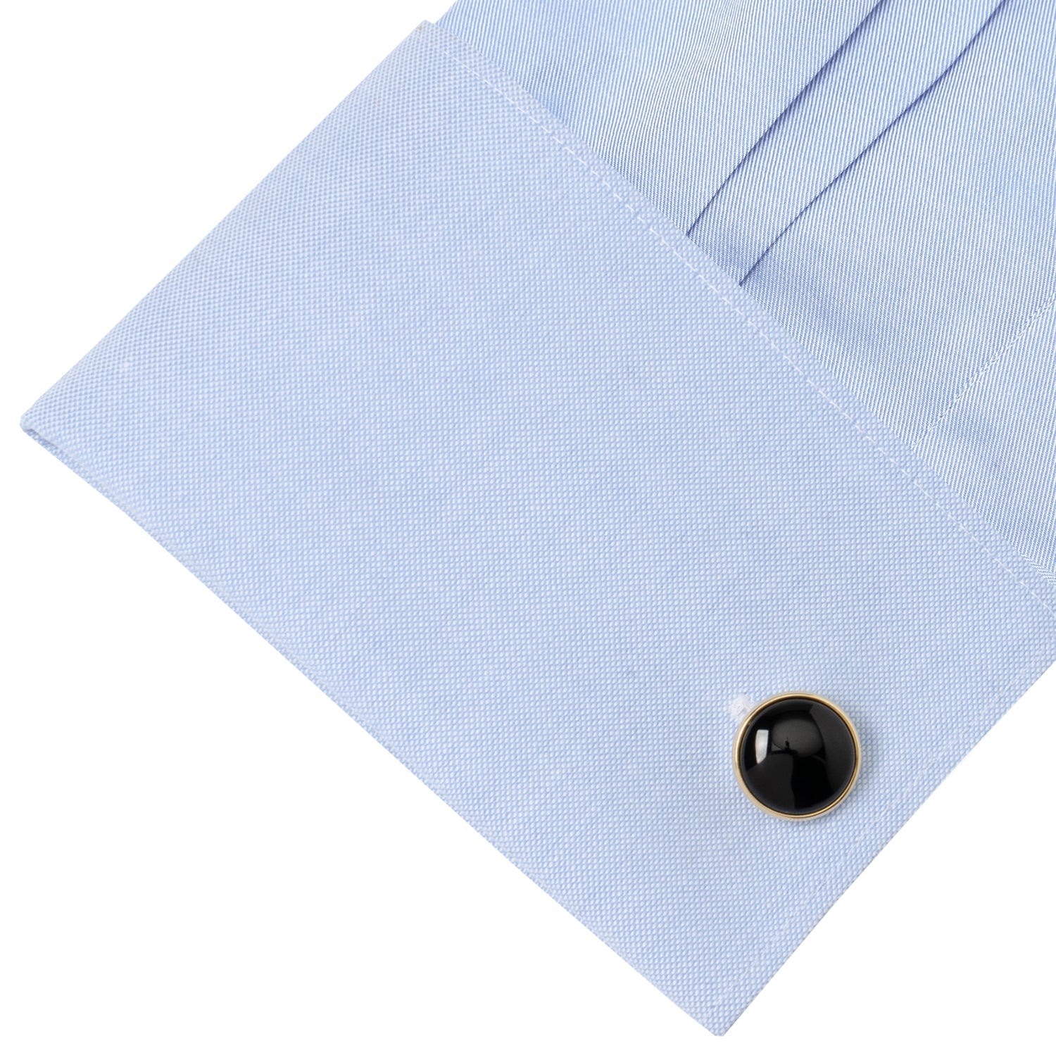 Black cufflink on a light blue dress shirt