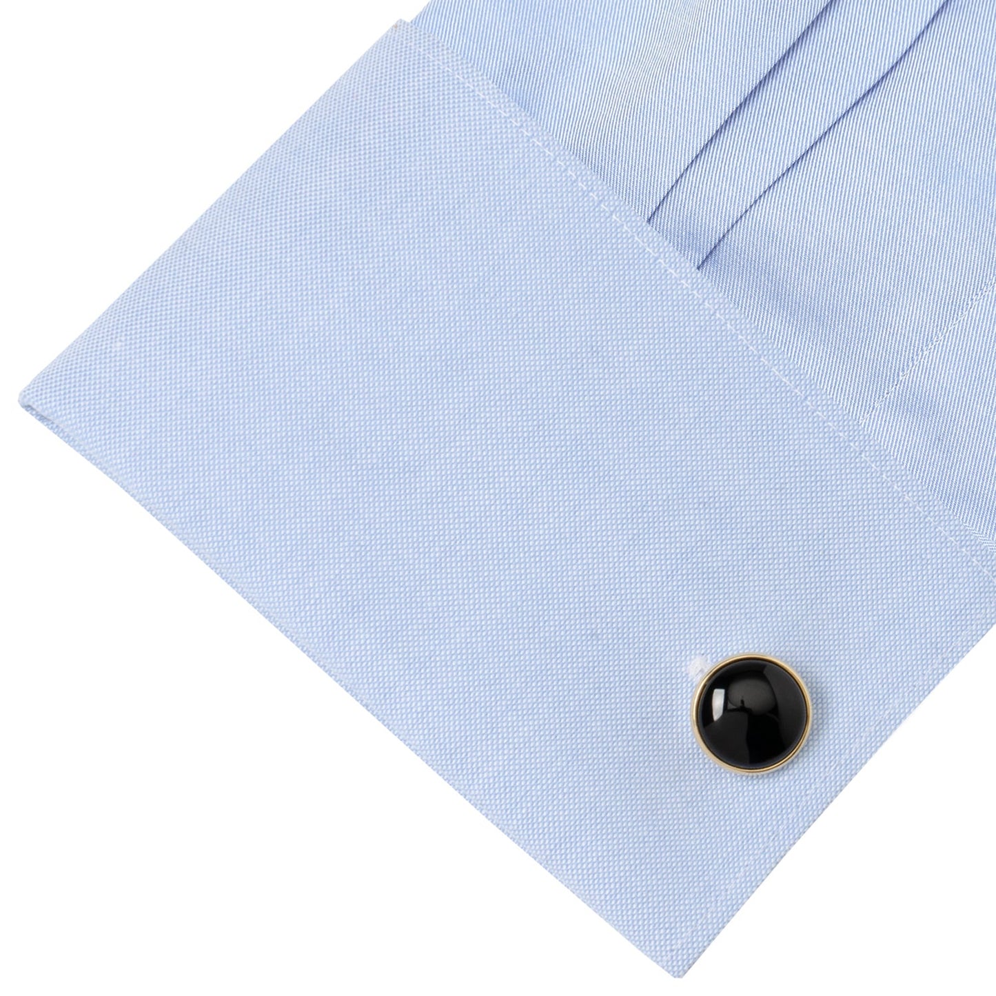 Black round cufflink on a light blue shirt