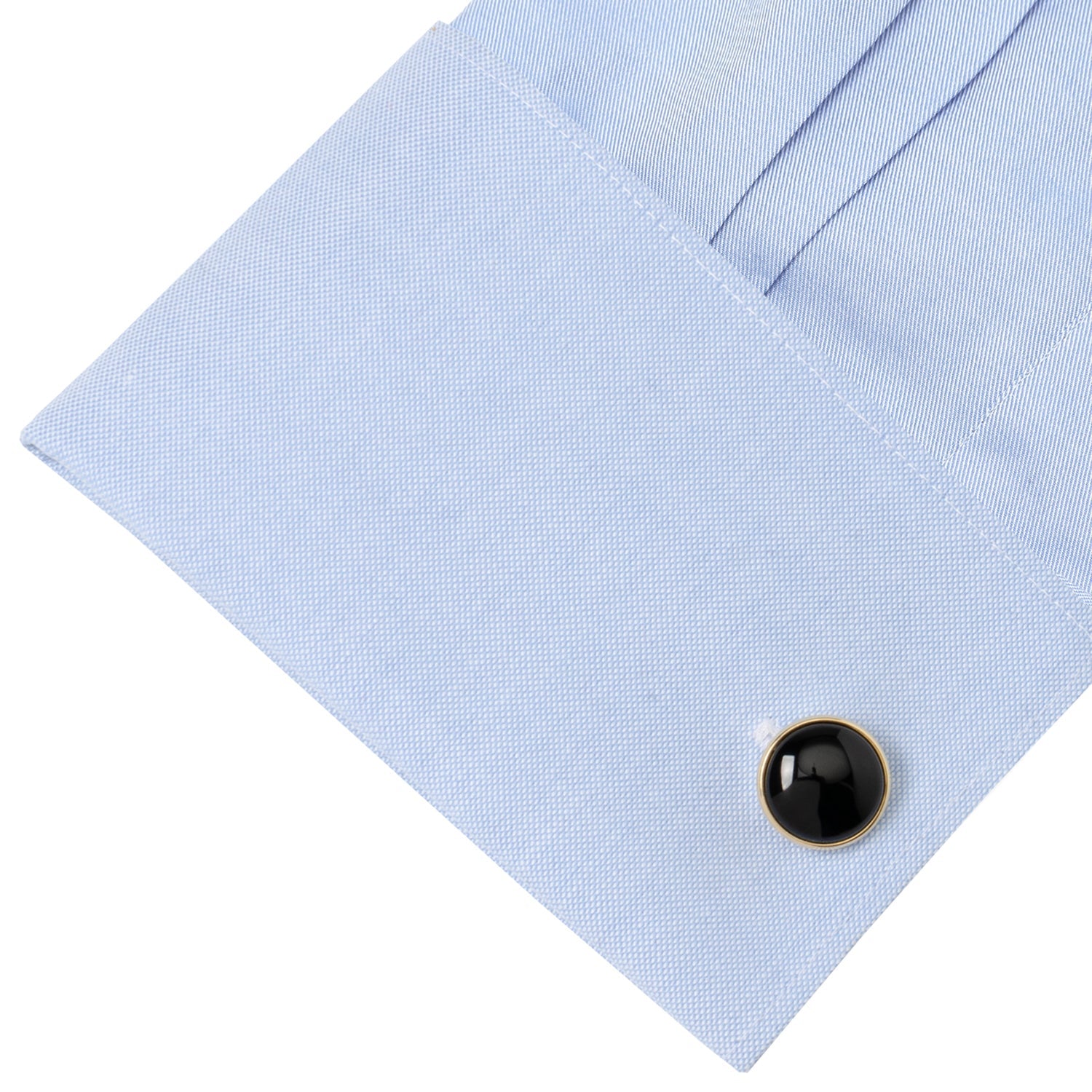 Black round cufflink on a light blue shirt