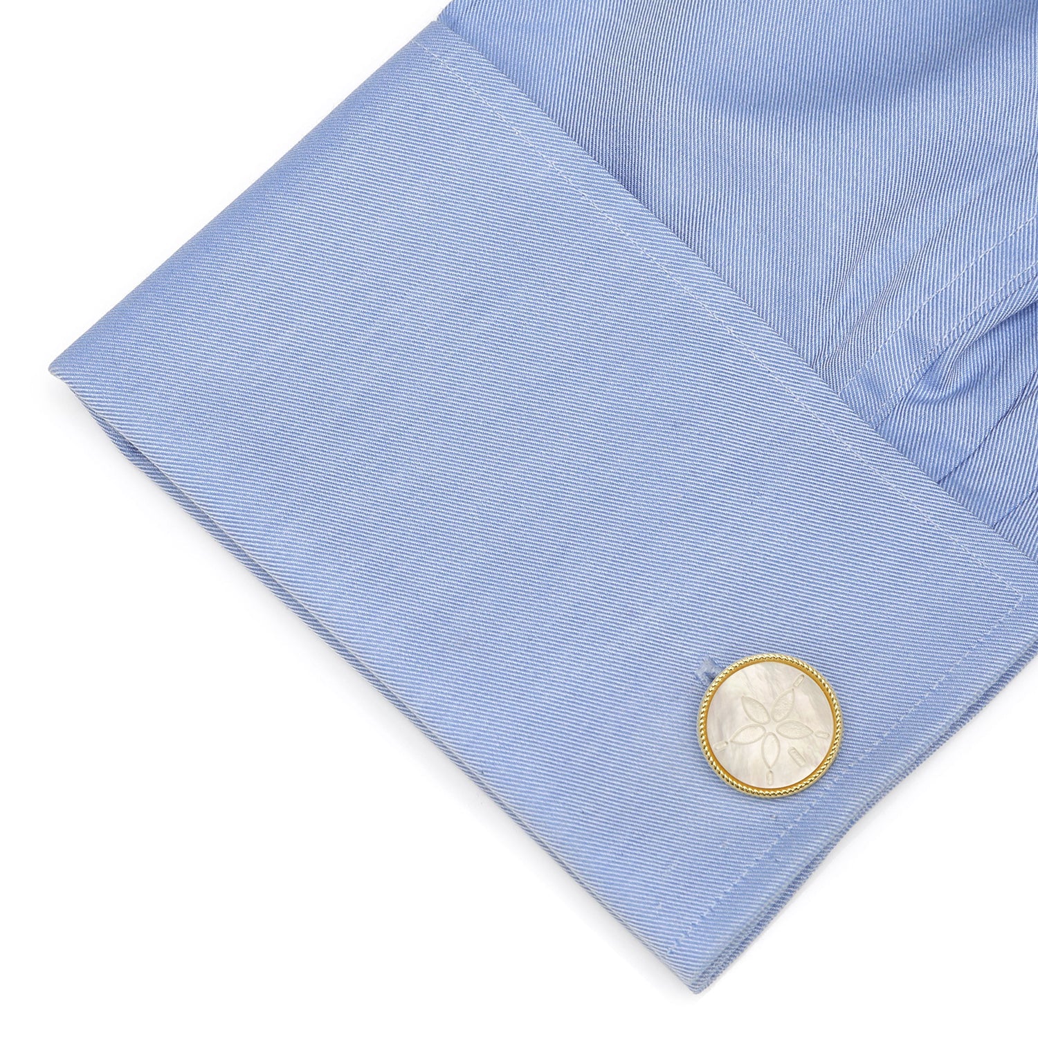 Close-up of a light blue shirt cuff with a cufflink on a white background