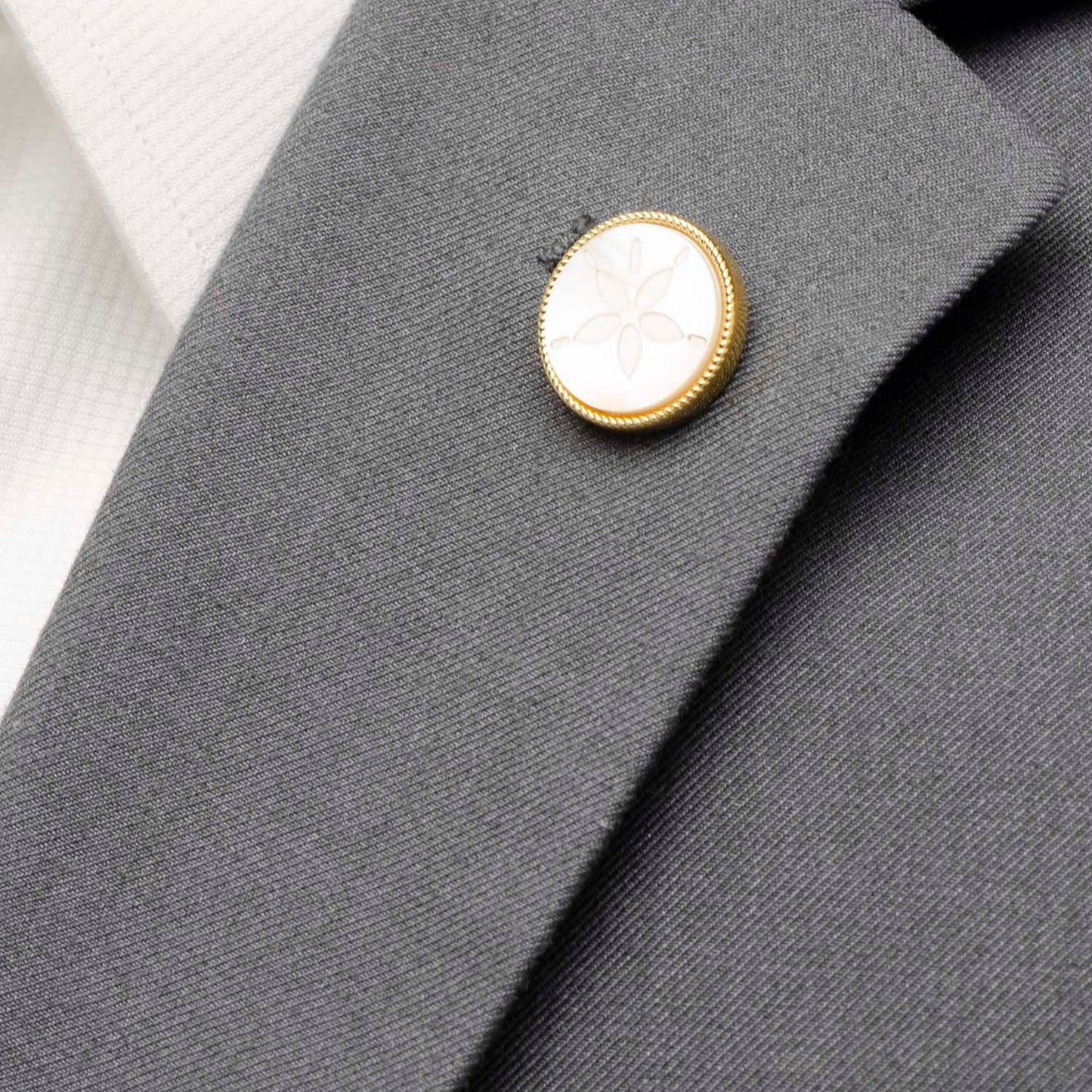 Close-up of a gray suit jacket with a gold and white button.