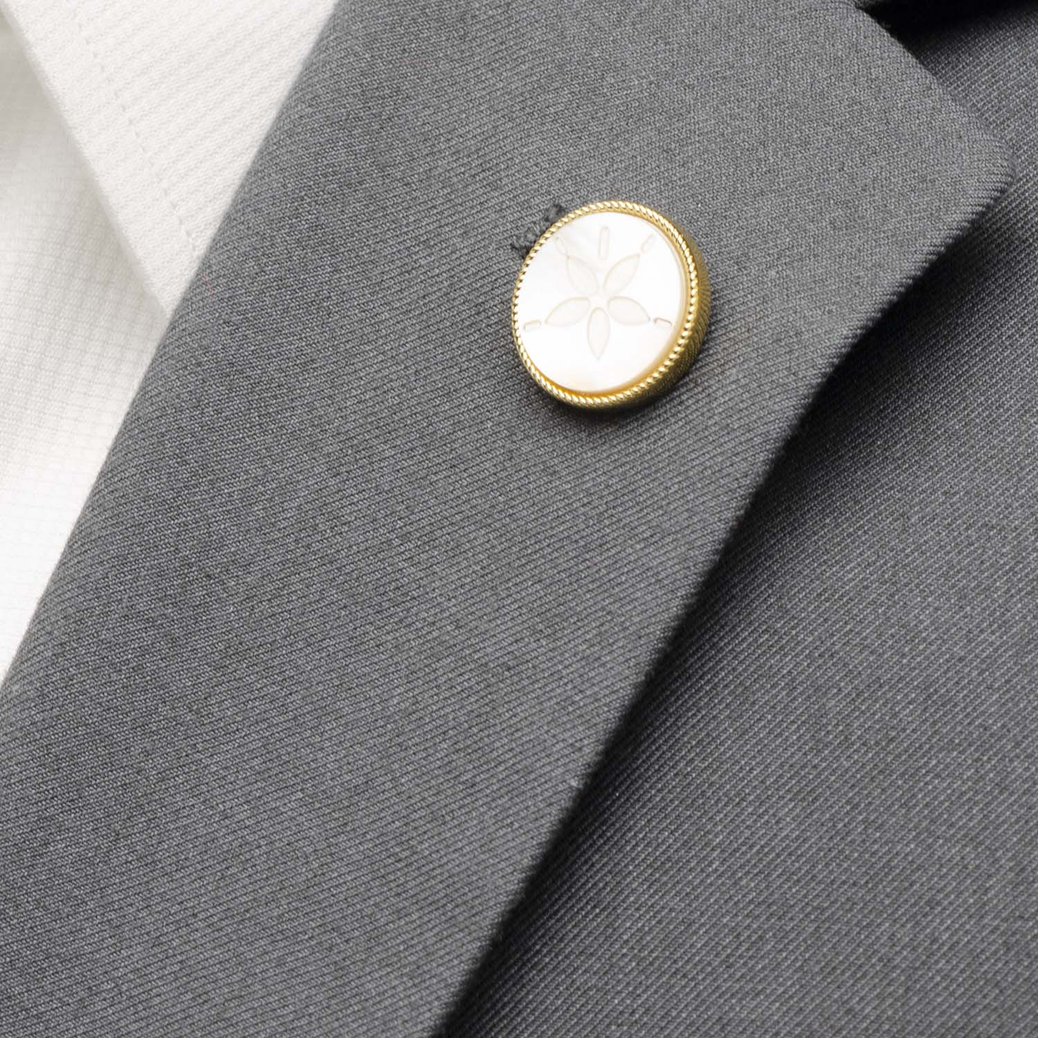 Close-up of a gray suit jacket with a gold and white button.