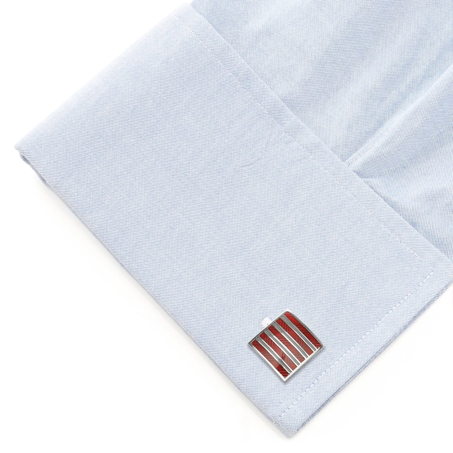 Cufflinks with a red and silver design on a light blue dress shirt.