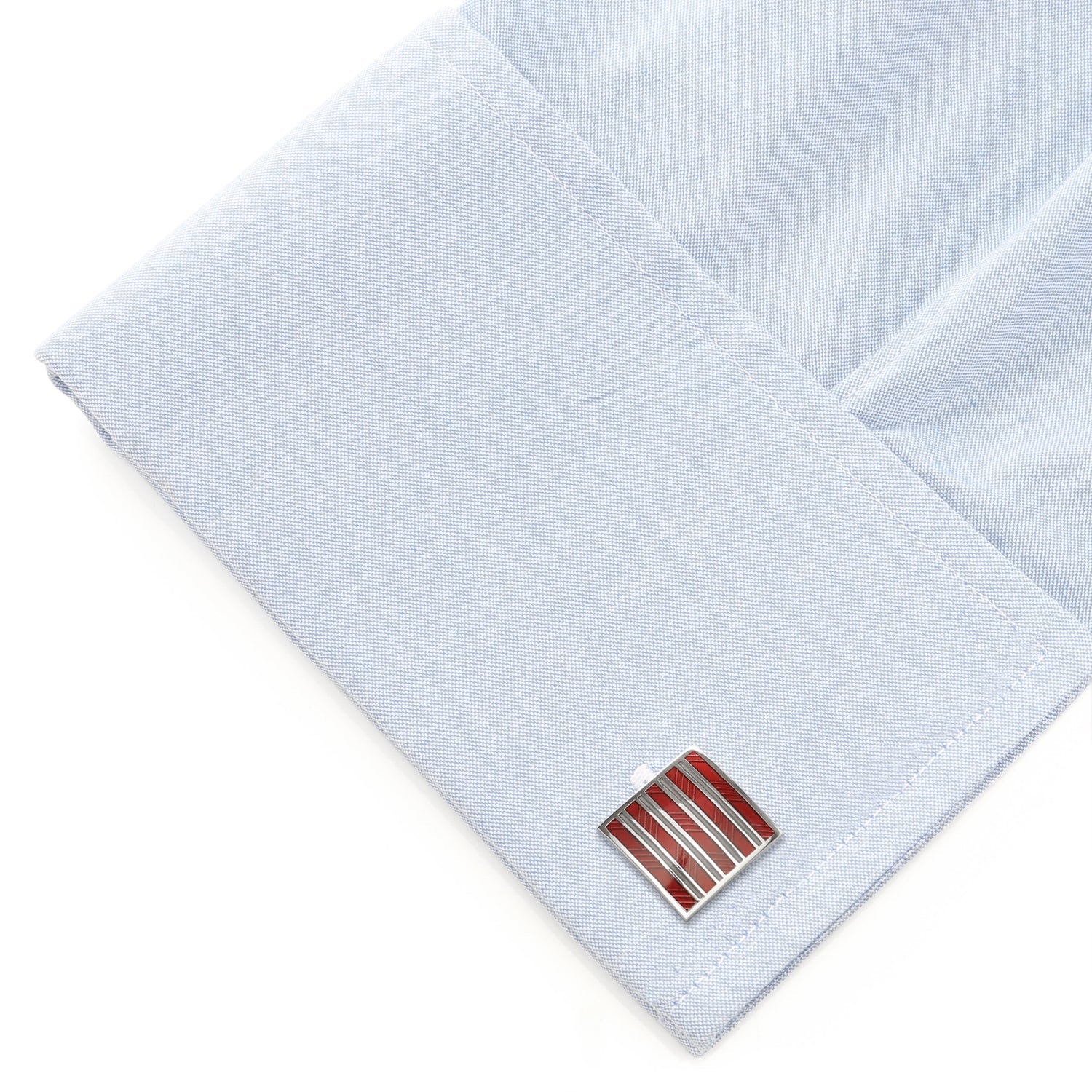 Cufflinks with a red and silver design on a light blue dress shirt.
