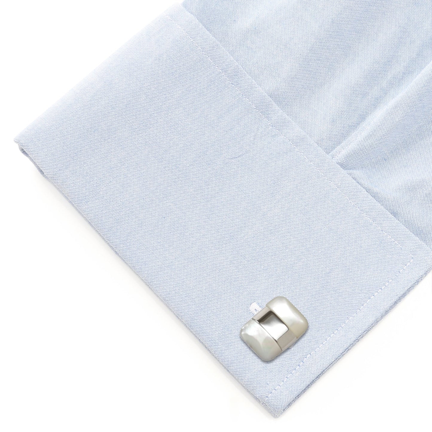 Silver cufflink on a light blue dress shirt