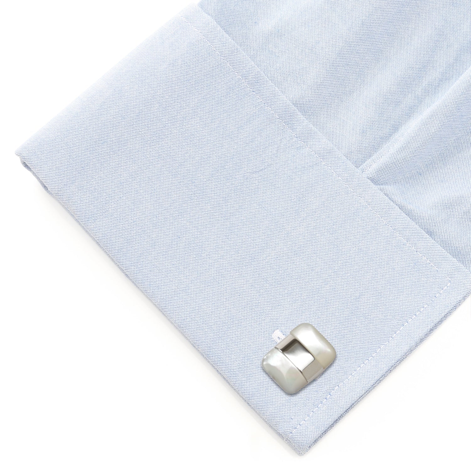 Silver cufflink on a light blue dress shirt