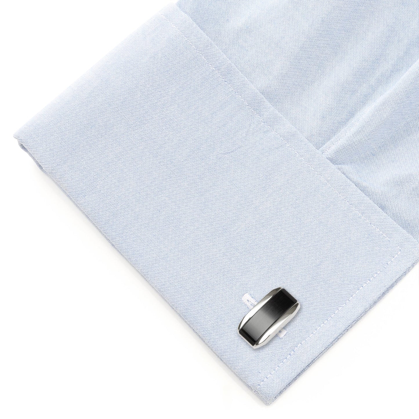 Cufflink on a light blue dress shirt with a white background