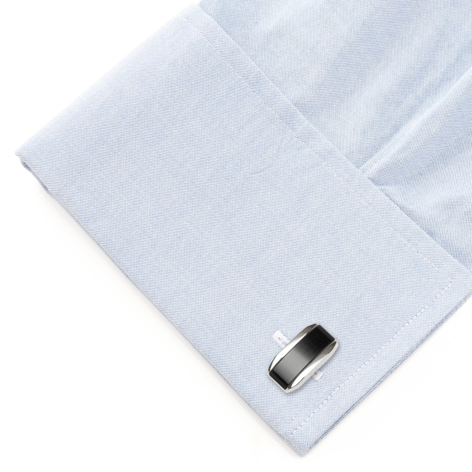 Cufflink on a light blue dress shirt with a white background