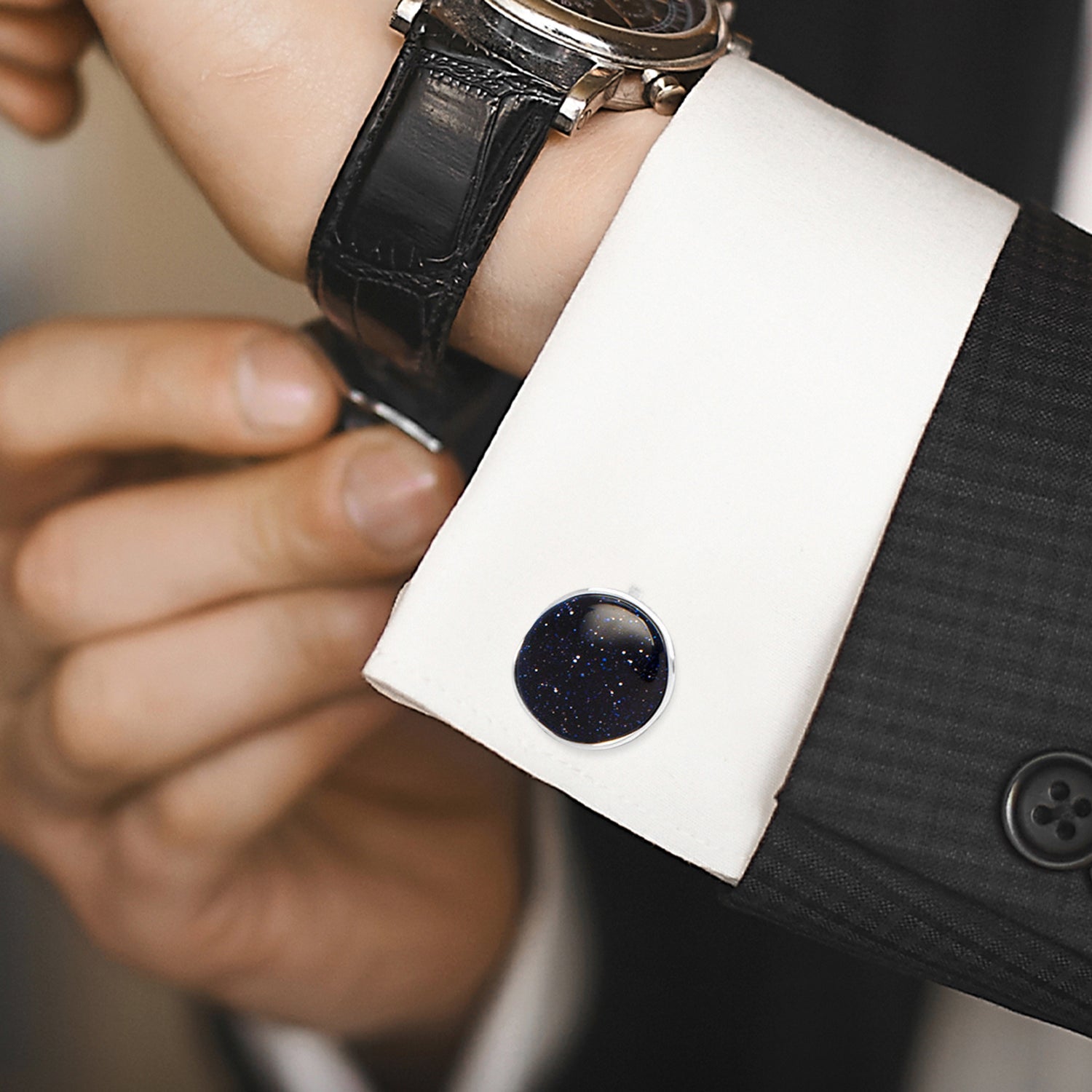 Close-up of a person wearing a black cufflink on a white shirt with a blurred background