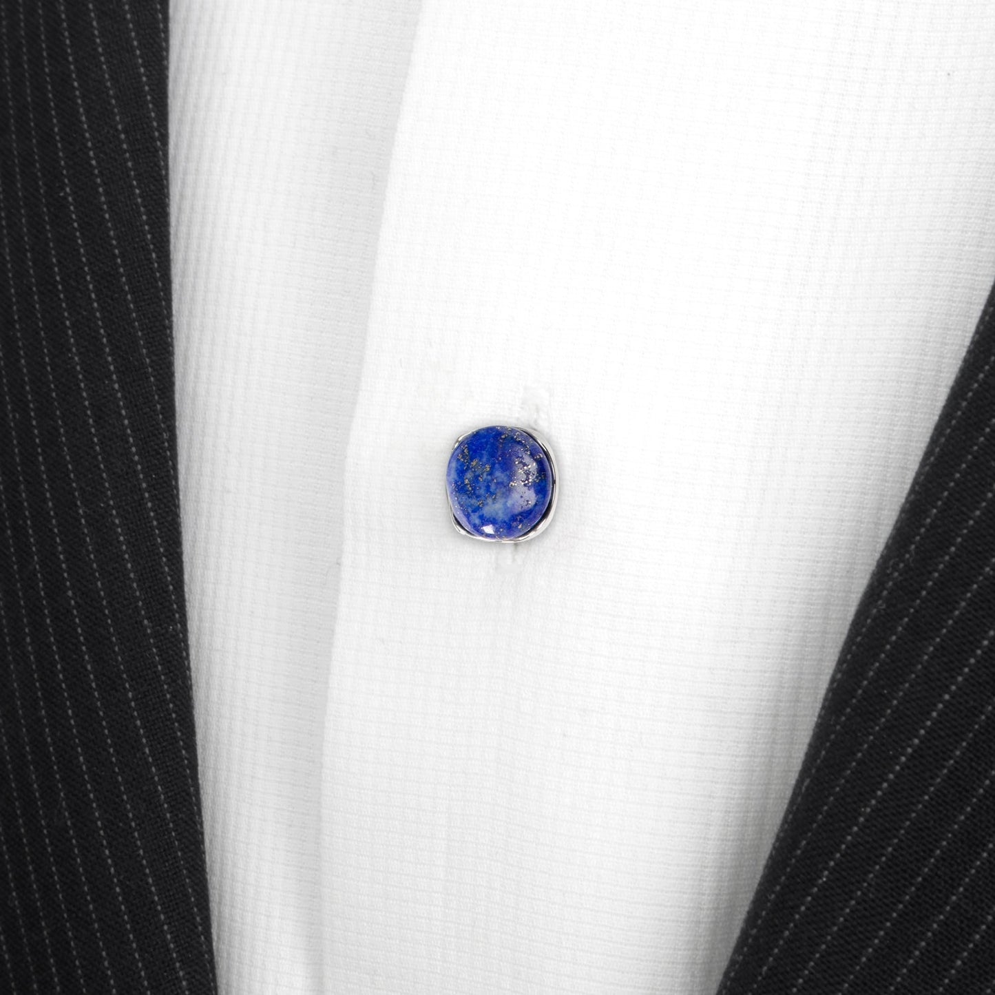 Blue gemstone button on a white shirt with black pinstripes