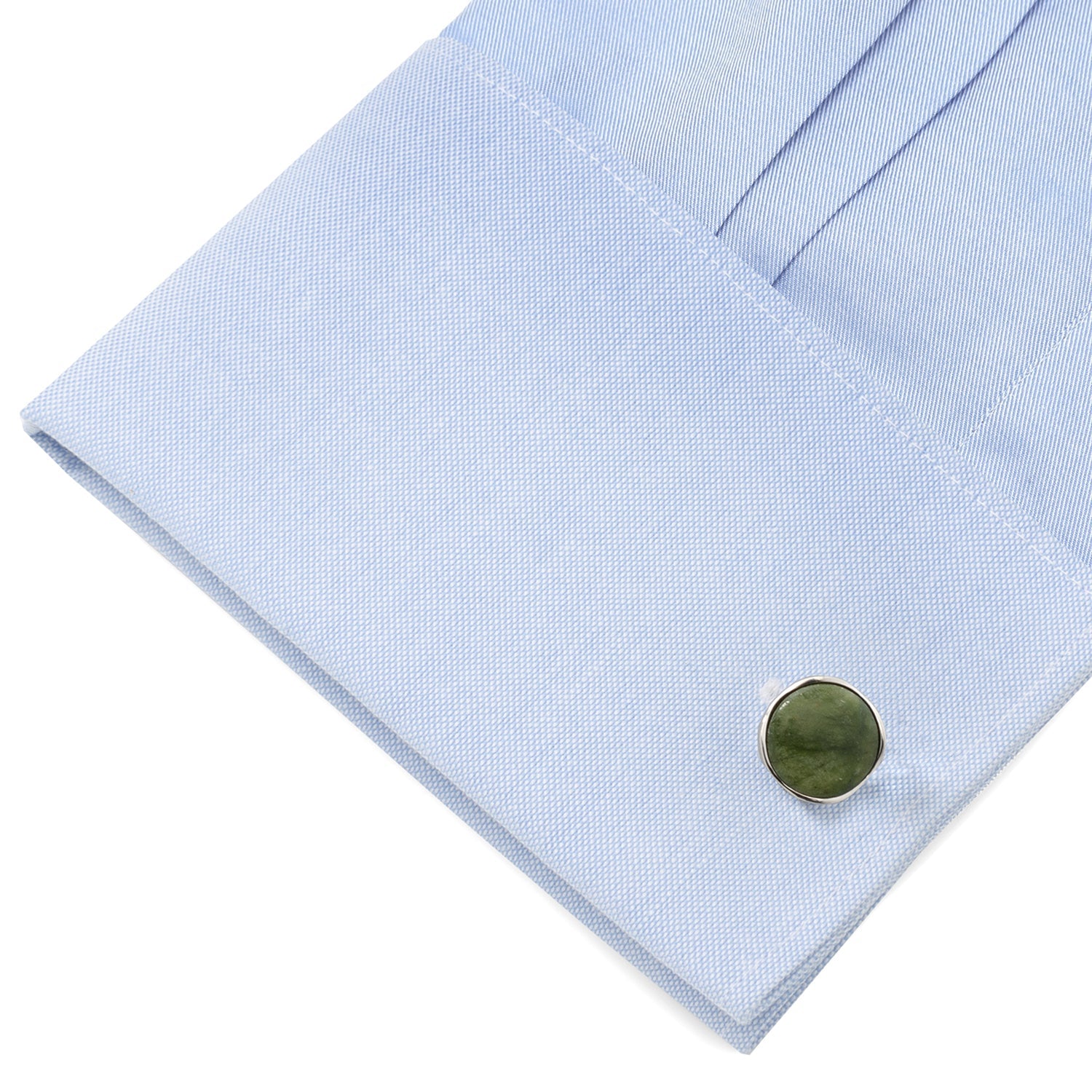 Close-up of a light blue shirt cuff with a green button on a white background