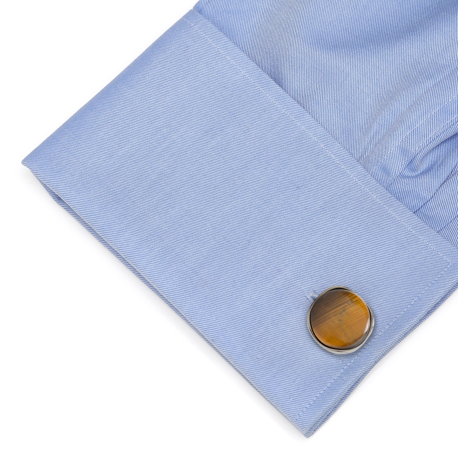 Close-up of a blue shirt cuff with a brown circular cufflink on a white background