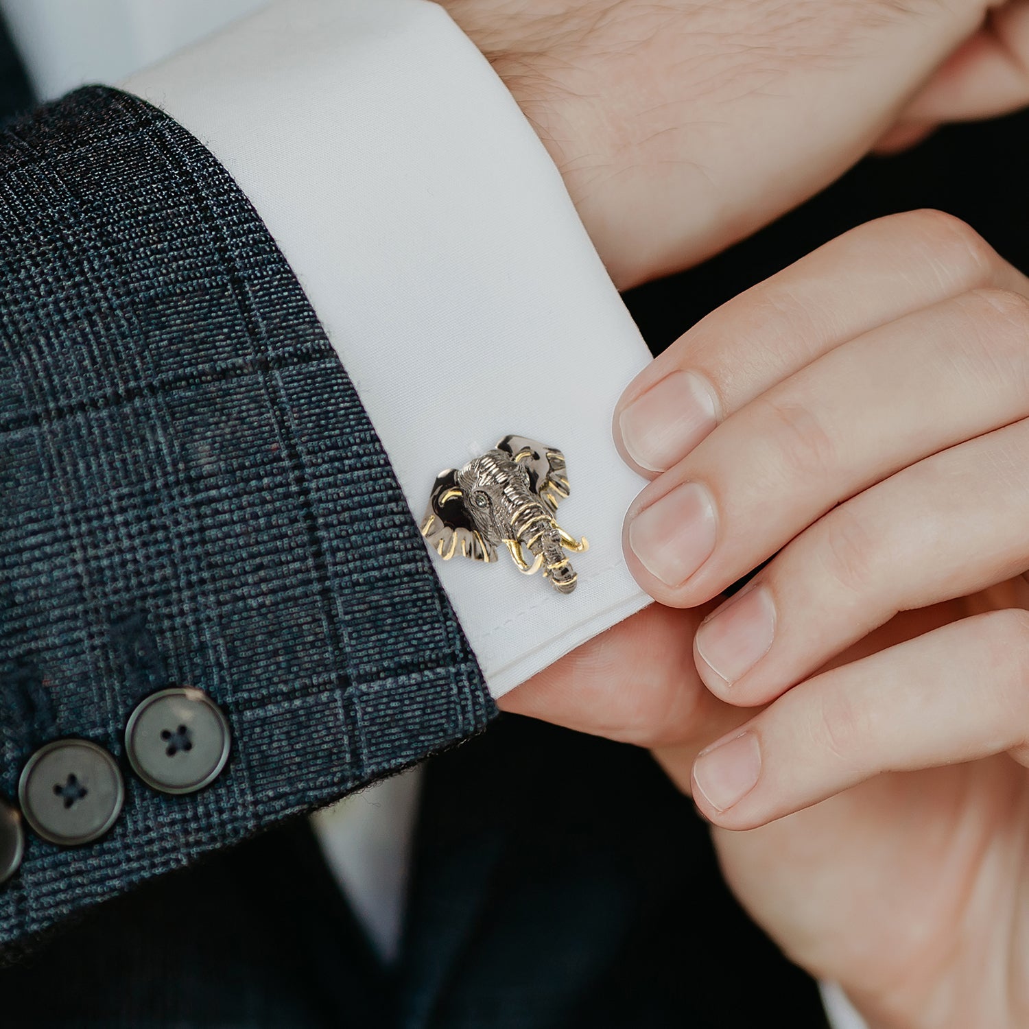 Cufflink being adjusted on a suit cuff with a close-up view.