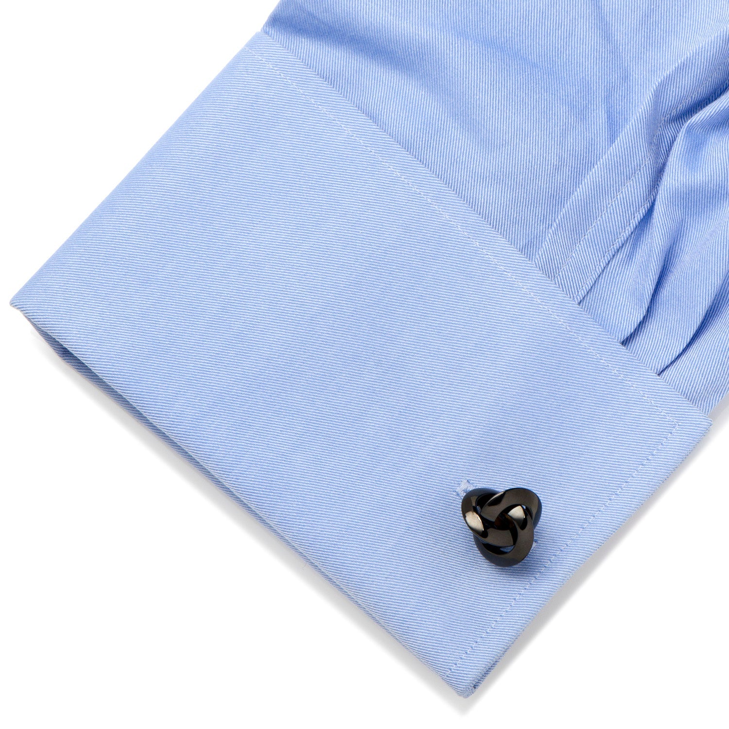 Black heart-shaped cufflink on a light blue shirt cuff