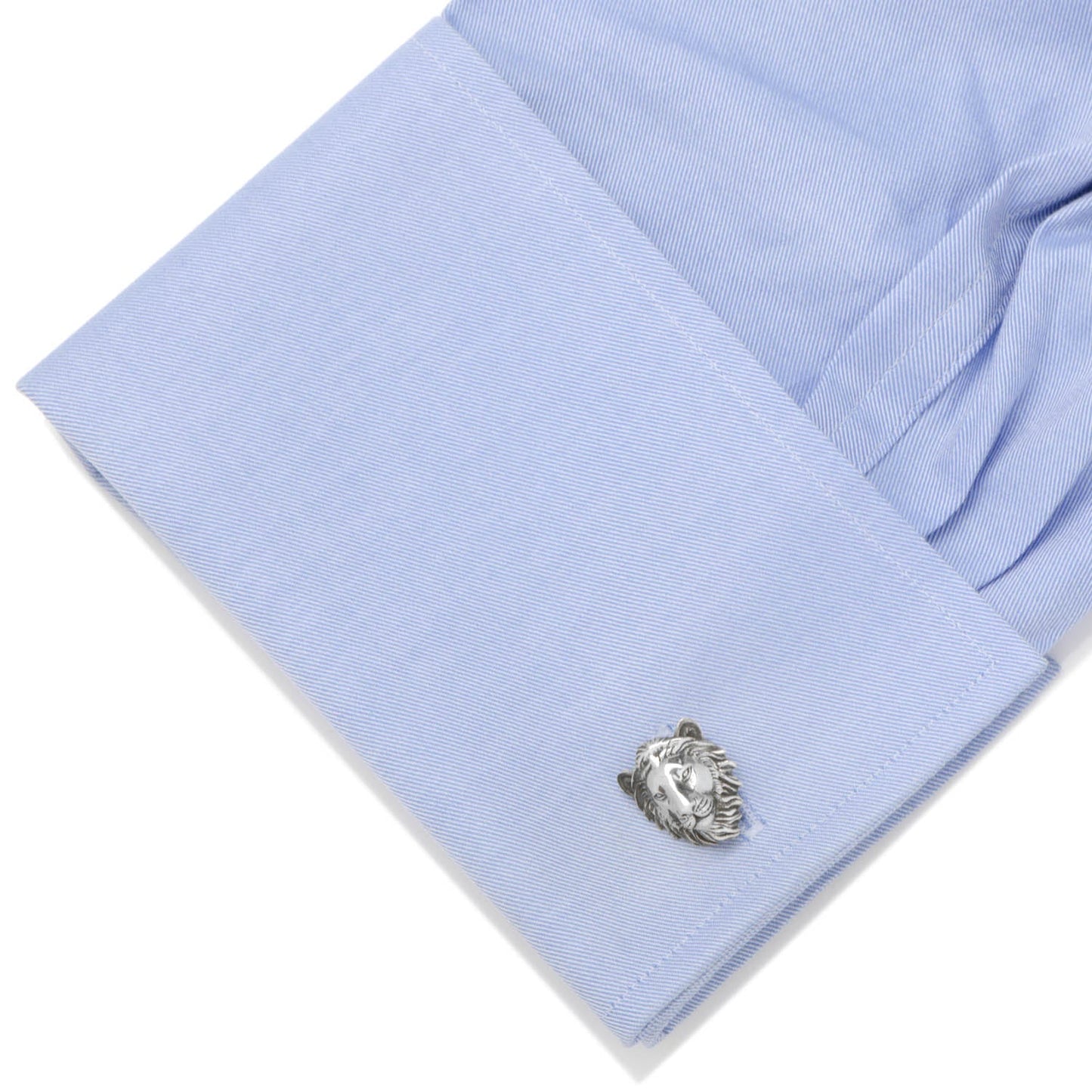 Close-up of a light blue shirt cuff with a silver cufflink on a white background