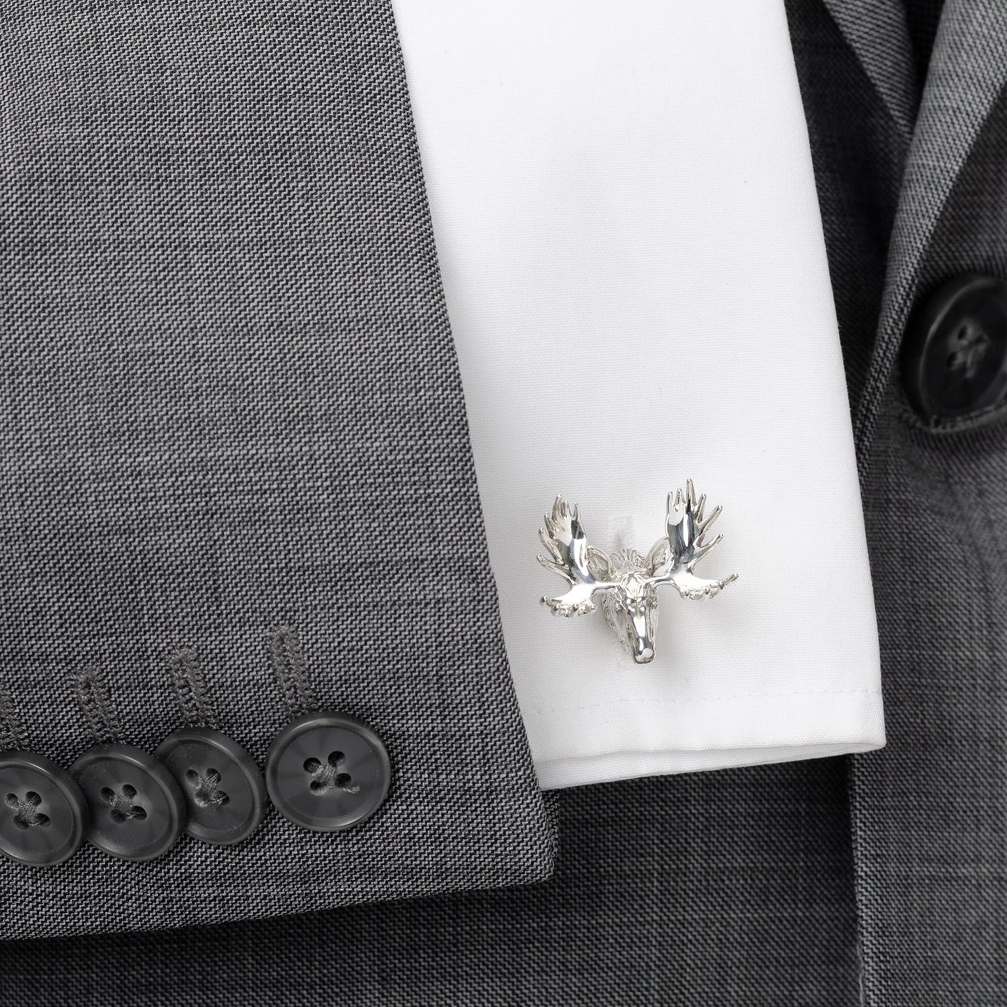 Silver moose head cufflinks on a white shirt against a gray suit background