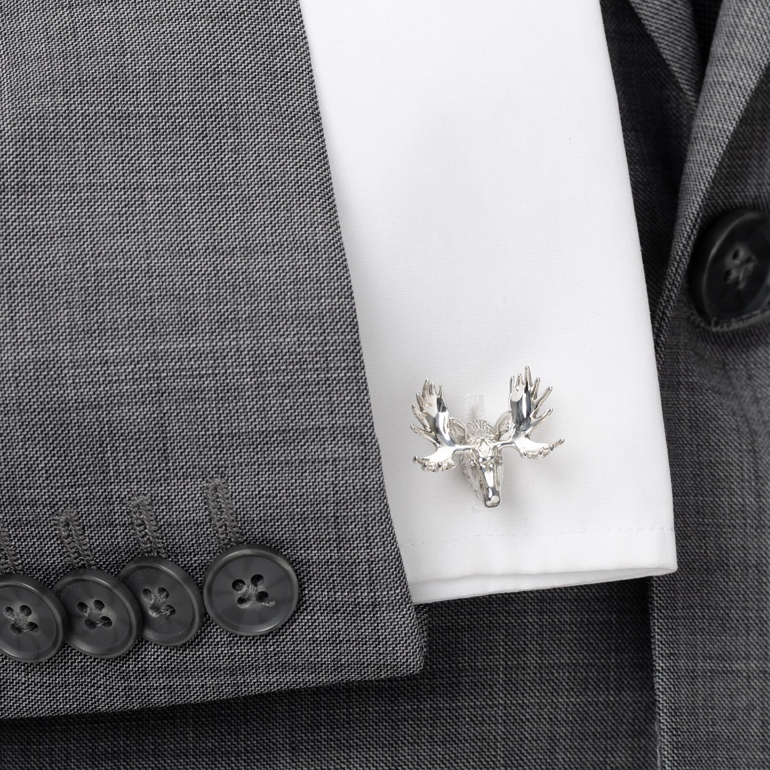 Silver moose head cufflinks on a white shirt against a gray suit background