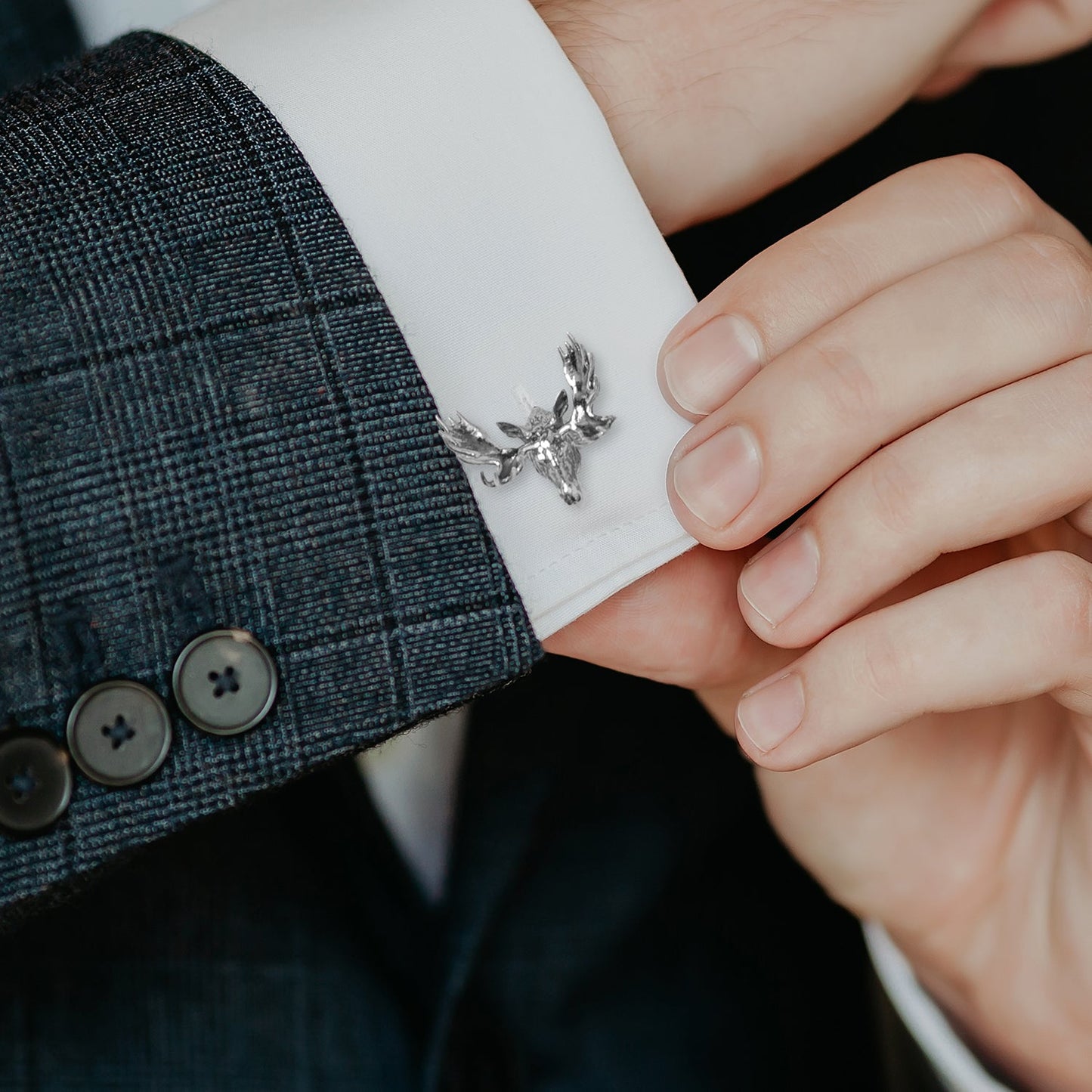 Cufflink being adjusted on a suit cuff with a close-up view.