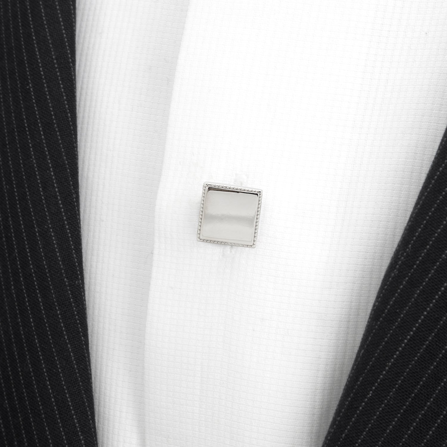 Close-up of a black pinstripe suit jacket with a white shirt and silver cufflink.