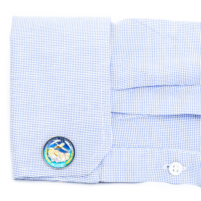 Close-up of a blue checkered shirt with a cufflink featuring a plane design on a white background