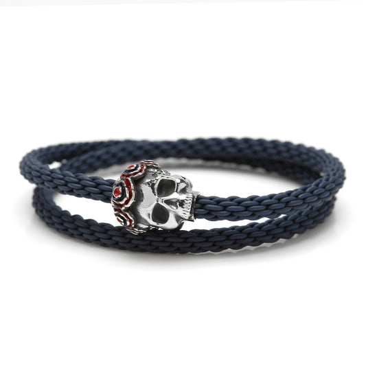 Navy blue braided bracelet with a silver skull charm on a white background