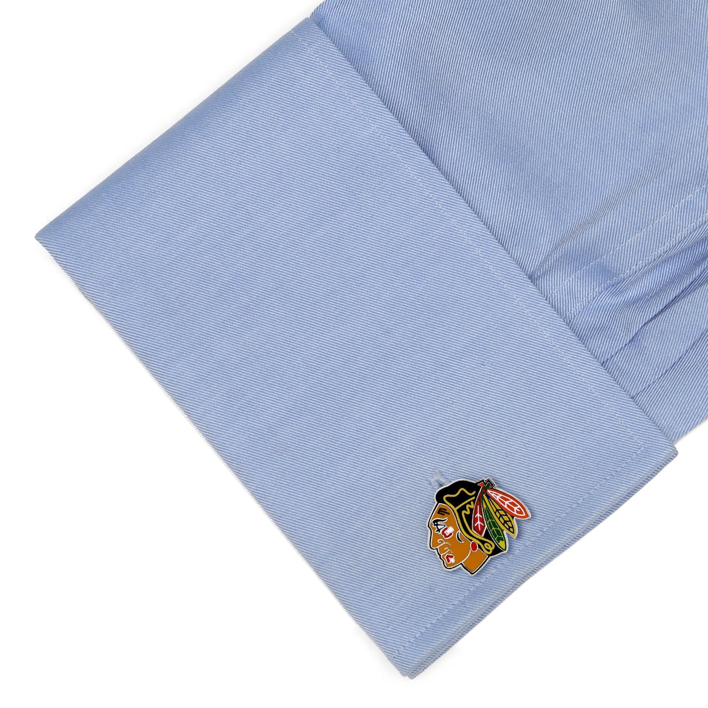 Cufflink with a logo on a light blue shirt cuff