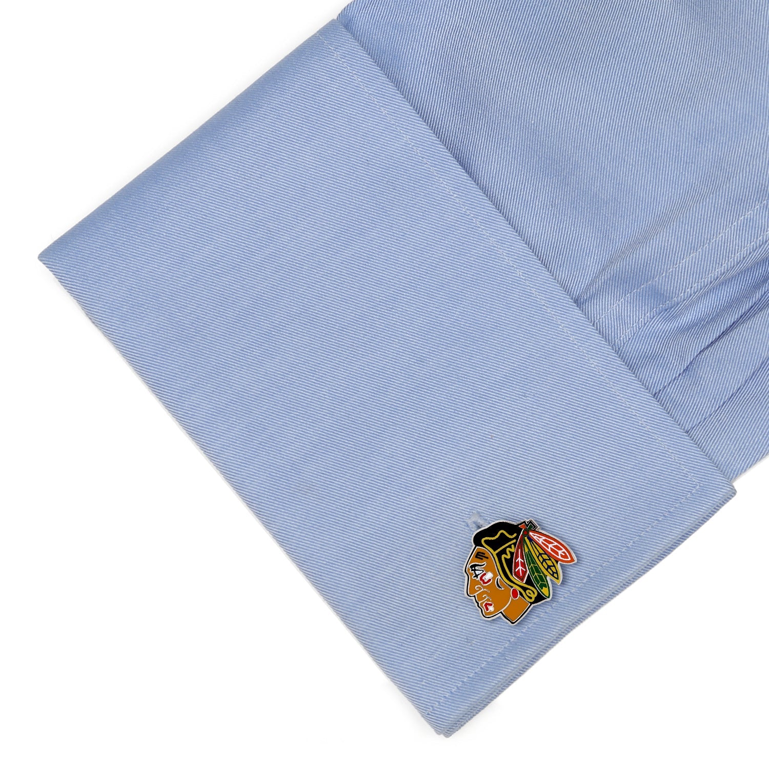 Cufflink with a logo on a light blue shirt cuff
