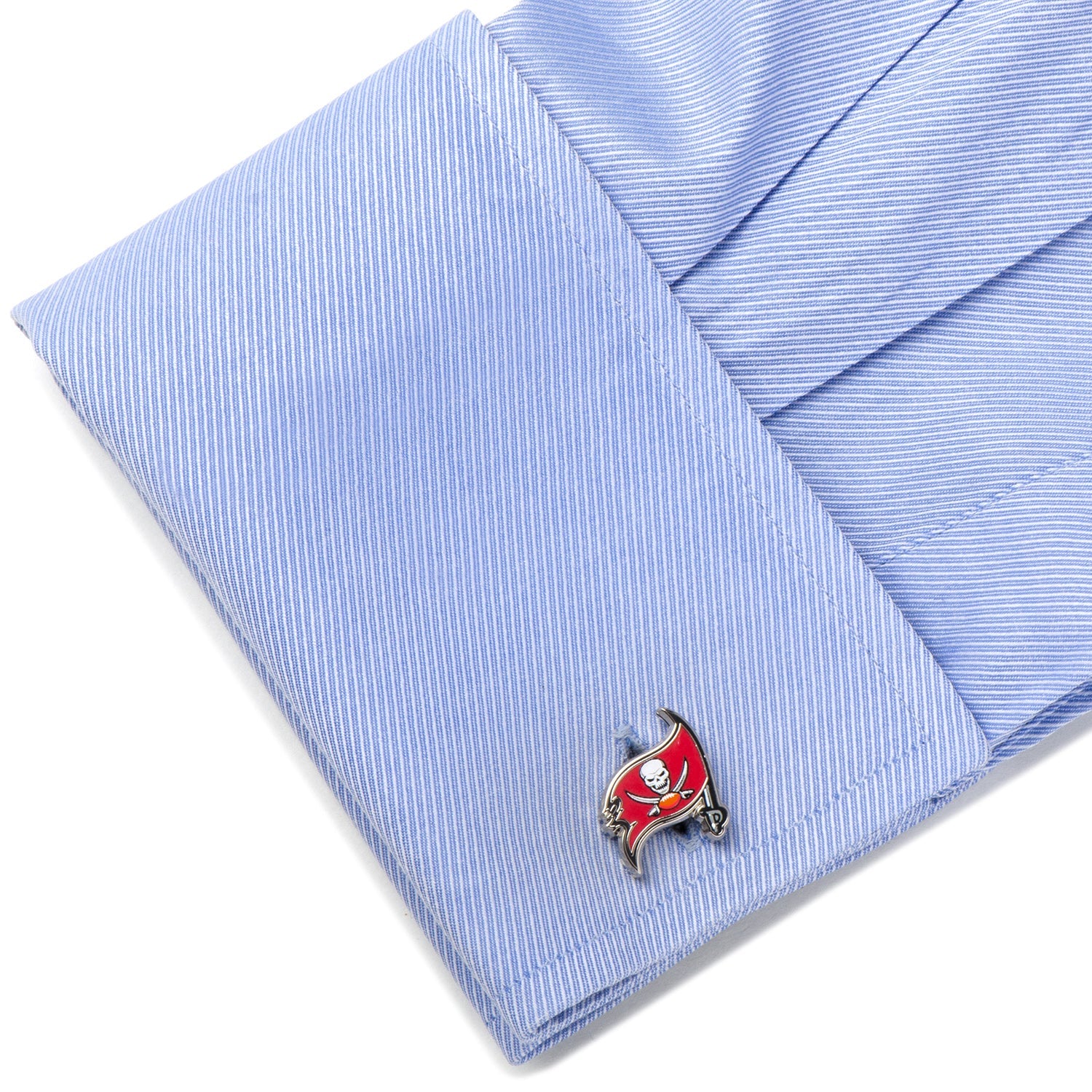 Cufflink with skull and crossbones design on a light blue striped shirt