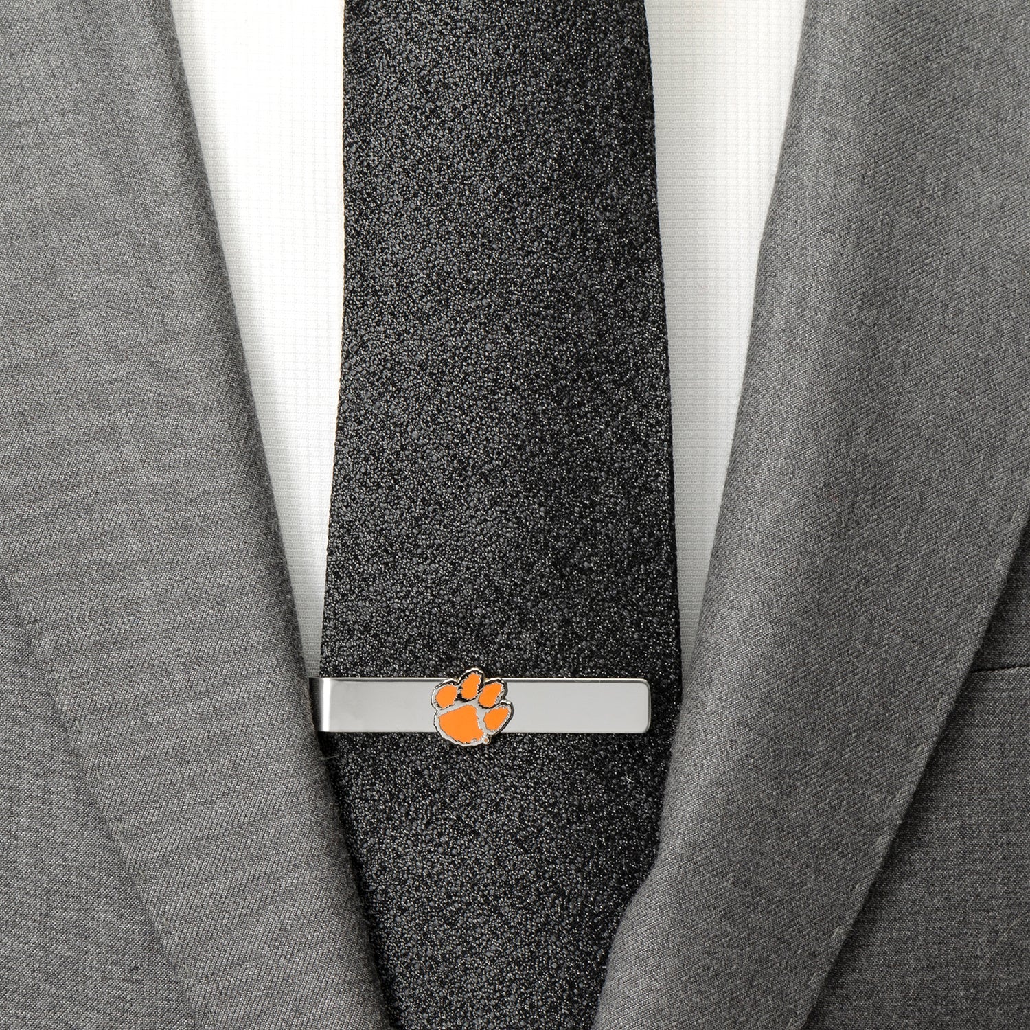Tie clip with a paw print design on a gray tie against a gray suit background