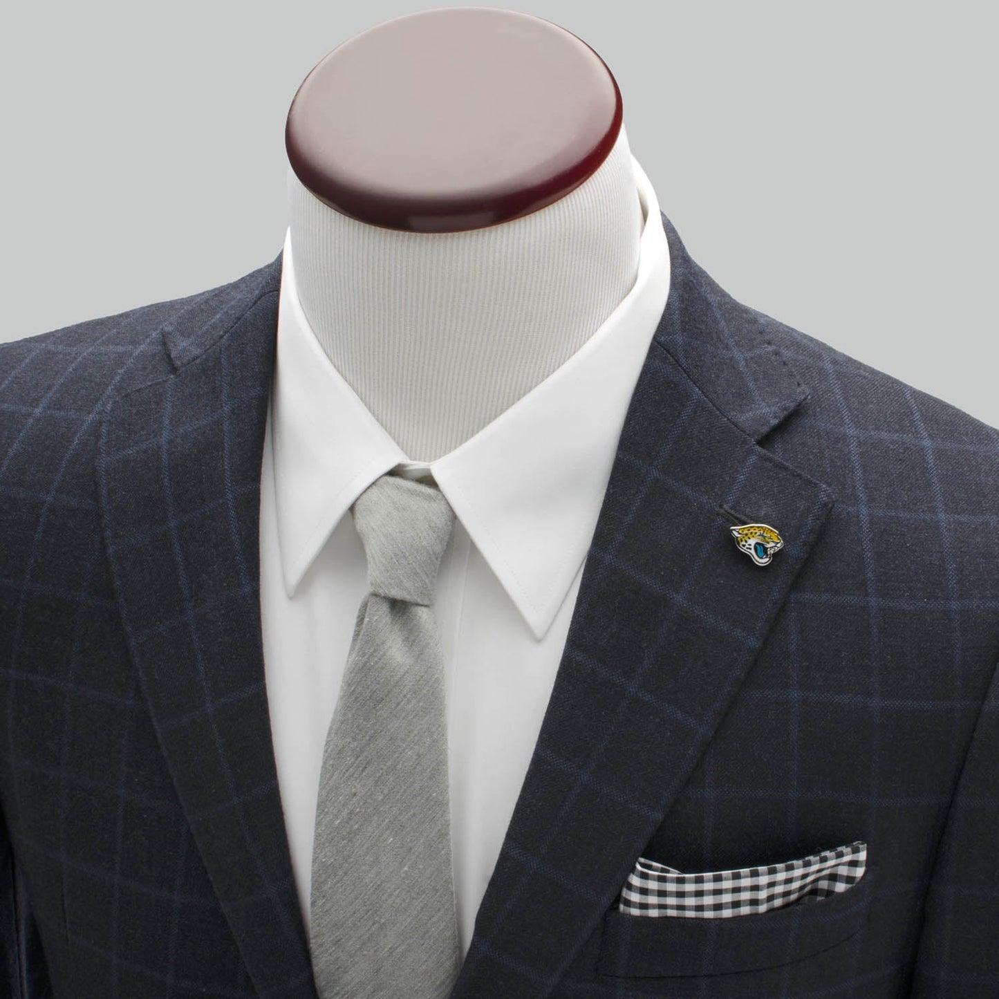 Gray checkered suit with white shirt, gray tie, and pocket square on a mannequin against a gray background.