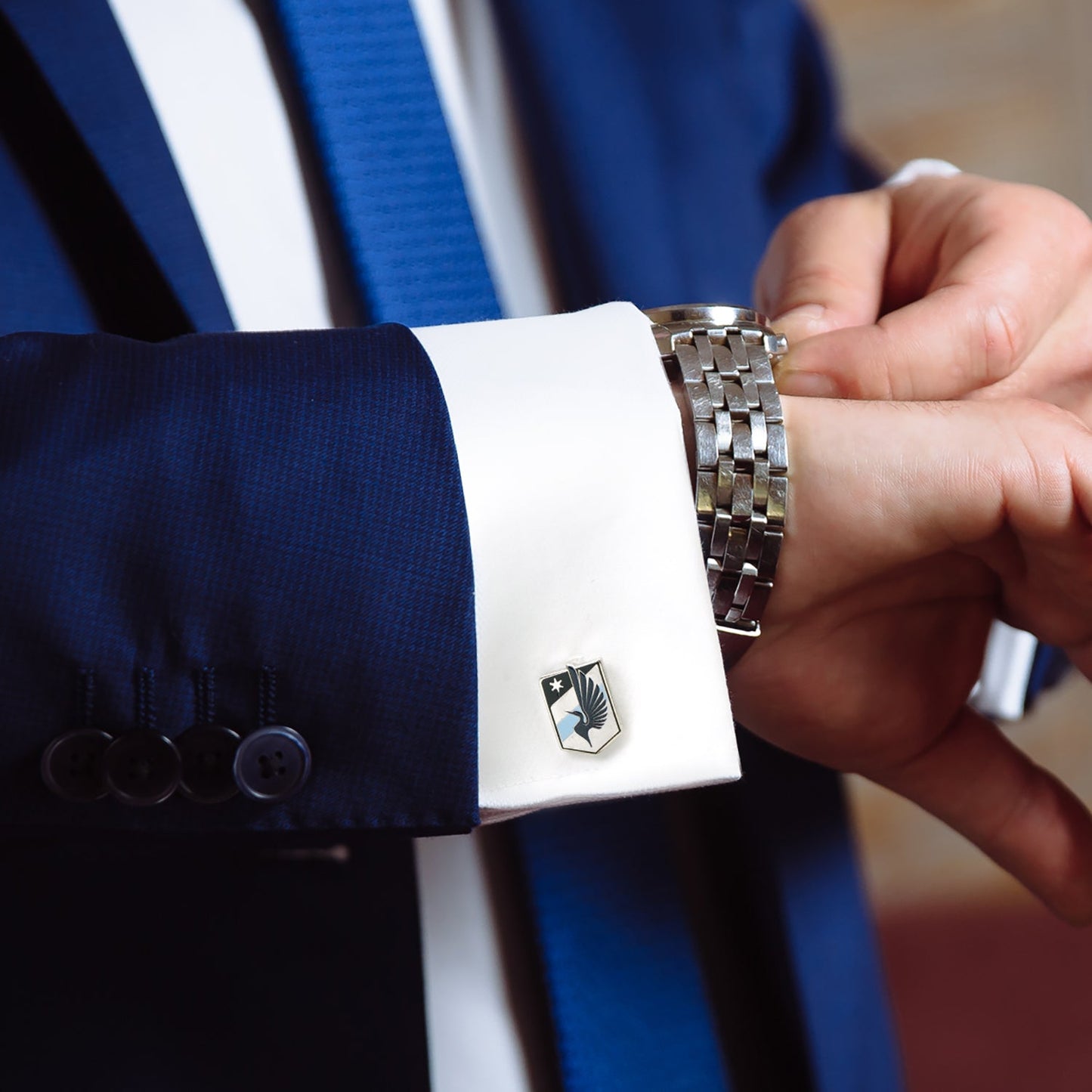 Close-up of a person adjusting a cufflink on a suit sleeve with a blurred background MLS Minnesota United Cufflinks 