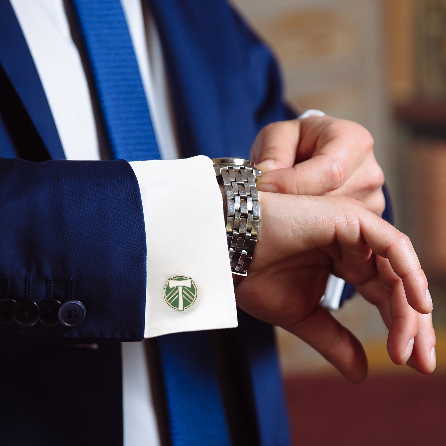 Close-up of a person wearing a suit with a cufflink and watch, blurred background