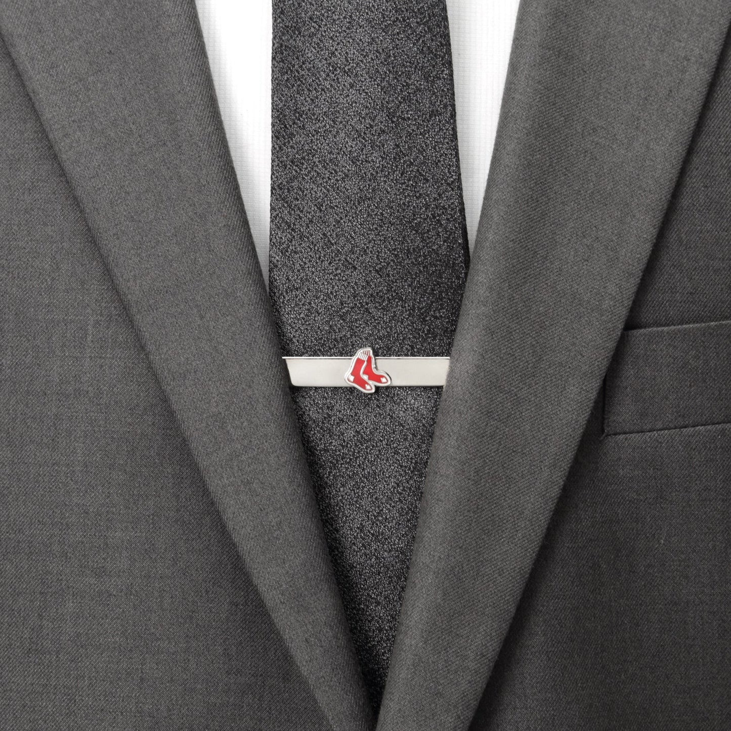 Gray suit with a gray tie and a silver tie clip with red accents.