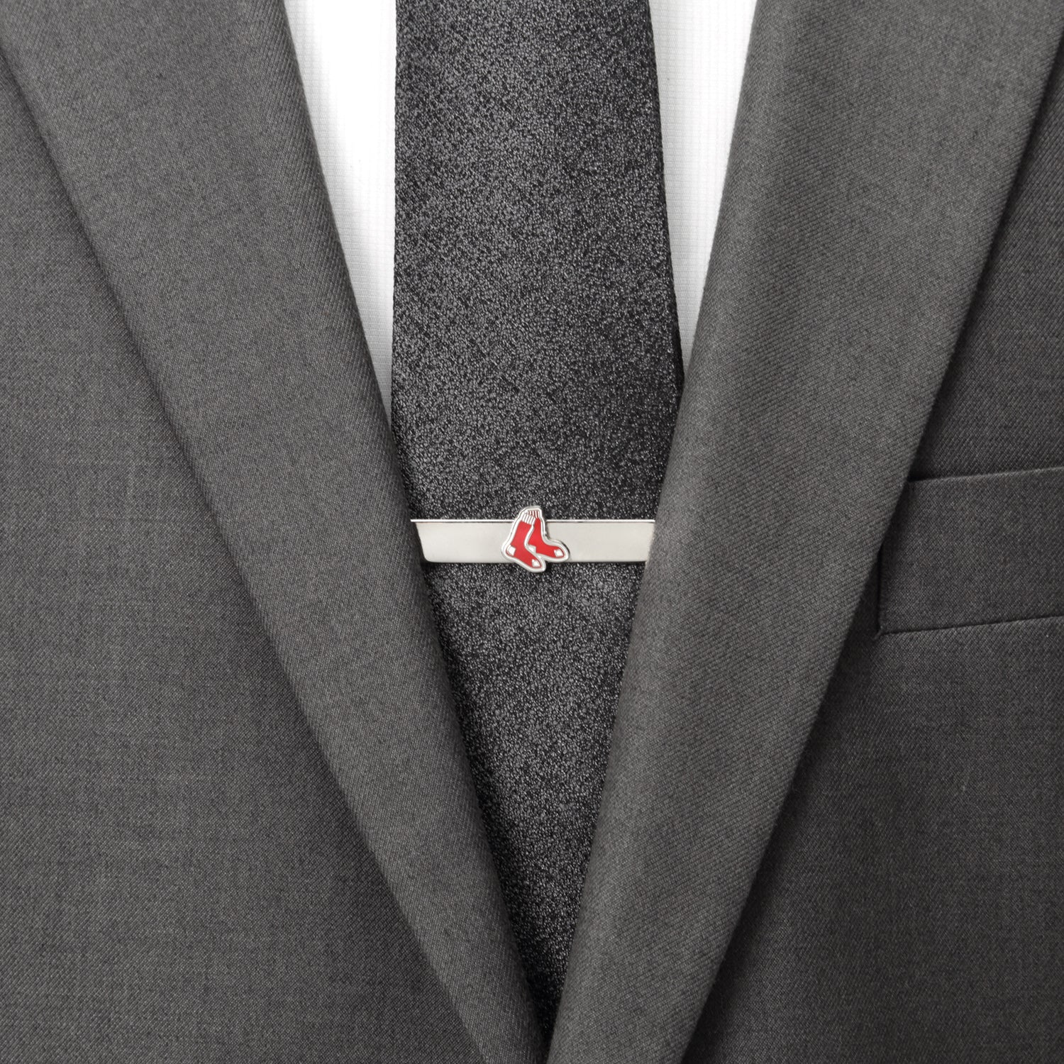 Gray suit with a gray tie and a silver tie clip with red accents.