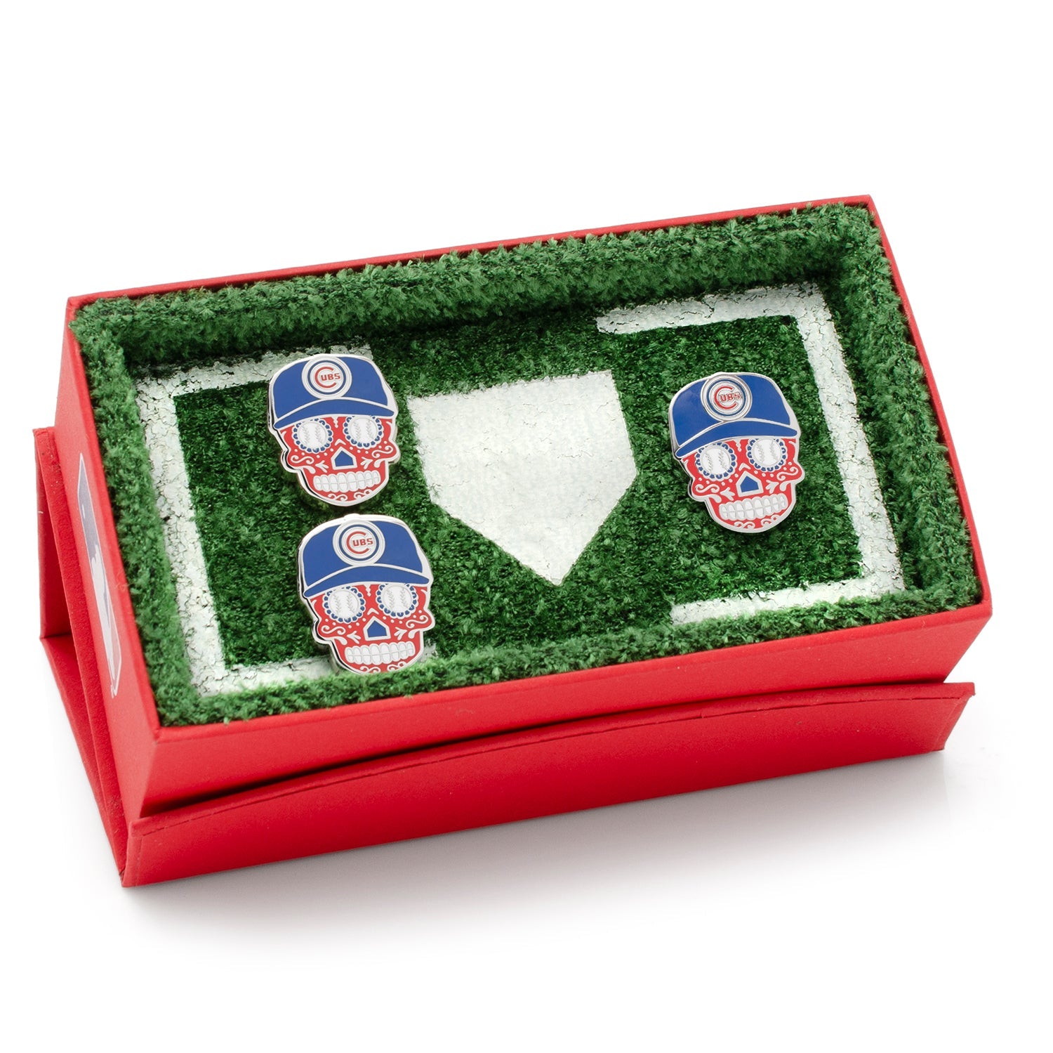 Three skull-shaped earrings with Chicago Cubs hats in a grassy display box.