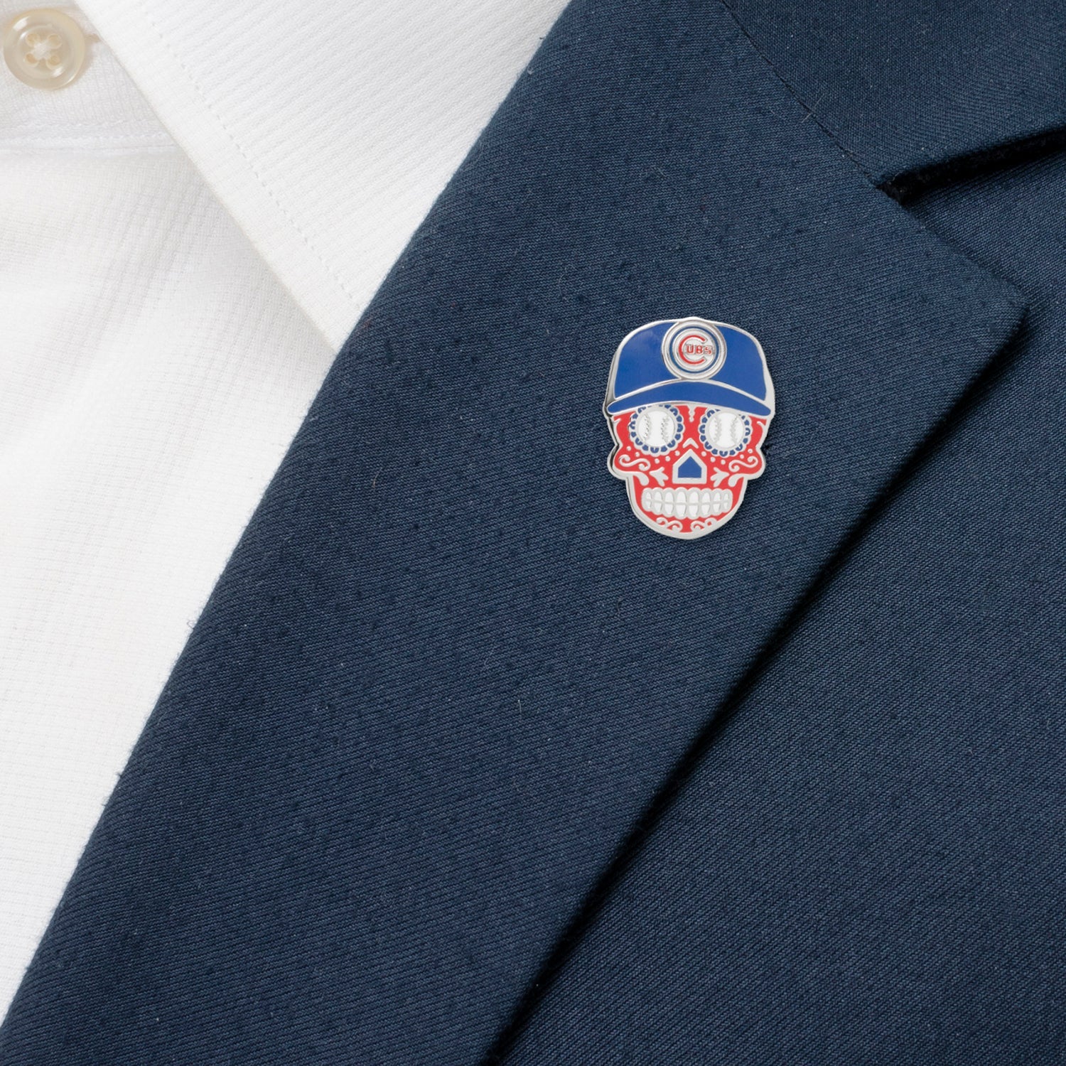 Navy blazer with a decorative skull pin featuring a baseball cap on a white shirt background