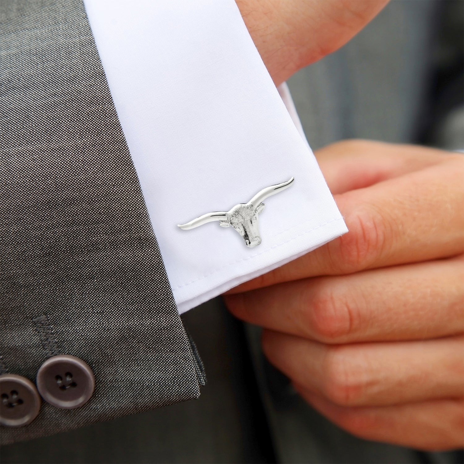 Cufflink on a white shirt cuff with a gray suit background