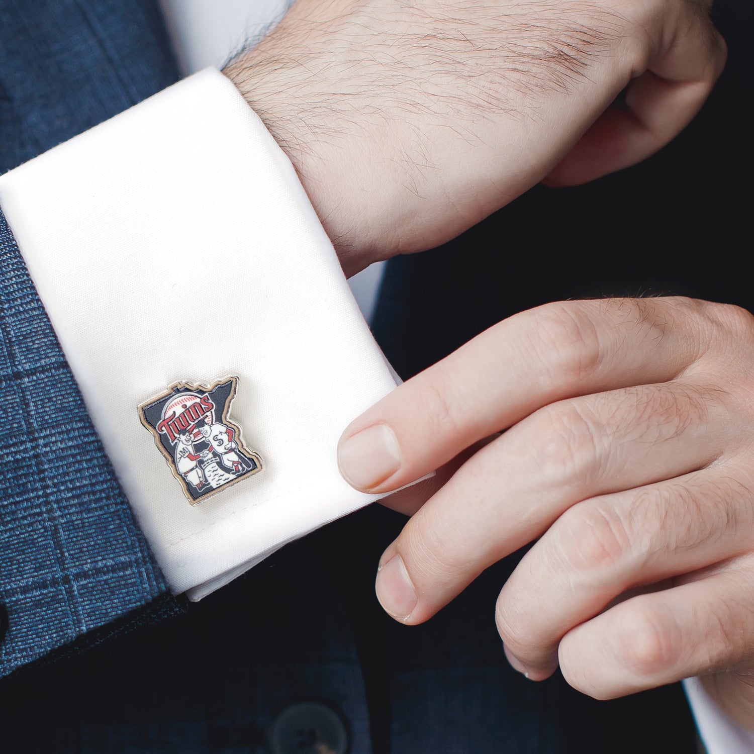 Cufflink with a logo on a white cuff against a dark suit background