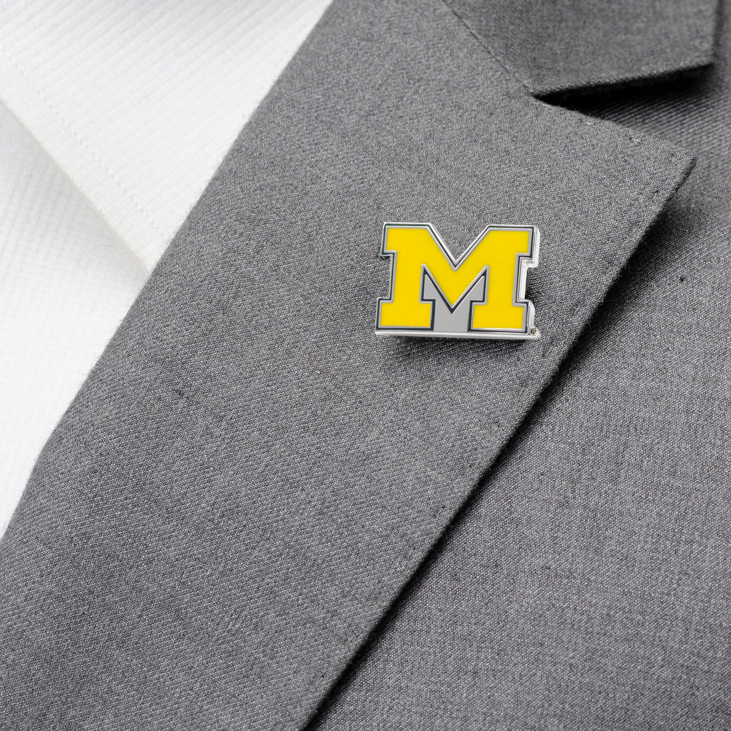 Yellow 'M' logo pin on a gray suit jacket
