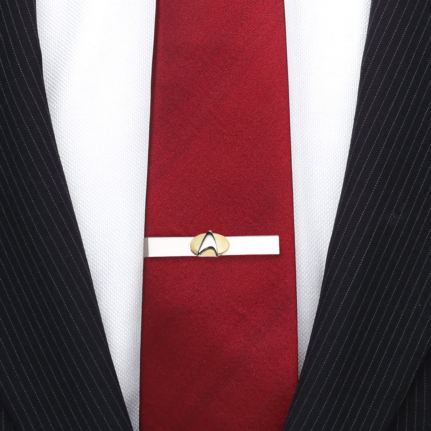 Red tie with a gold tie clip against a white shirt and black pinstripe suit. Star Trek Two Tone Delta Shield Tie Bar