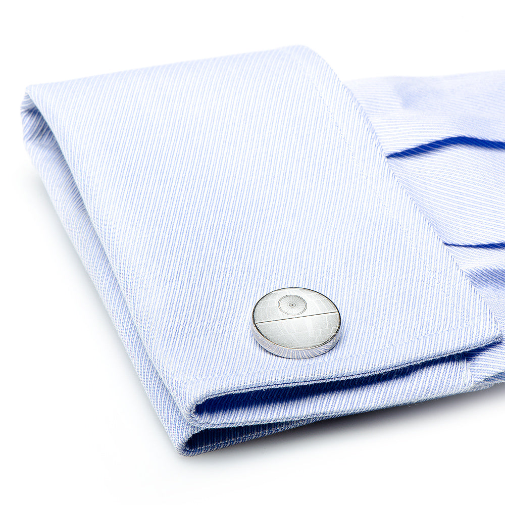Folded light blue dress shirt with a silver cufflink on a white background