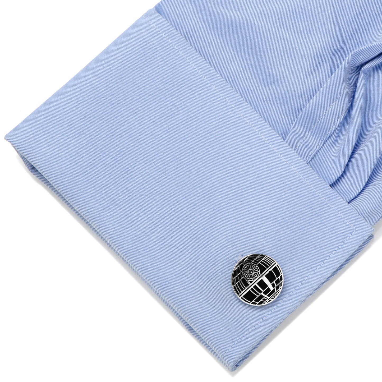 Cufflink on a light blue shirt with a white background